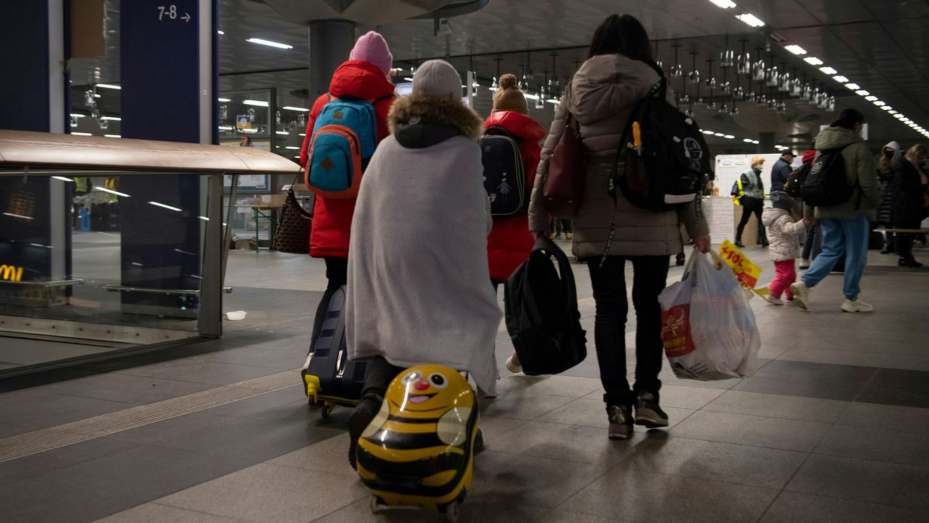 Flüchtlinge aus dem ukrainischen Kriegsgebiet gehen im Berliner Hauptbahnhof zu einer Sammelstelle.