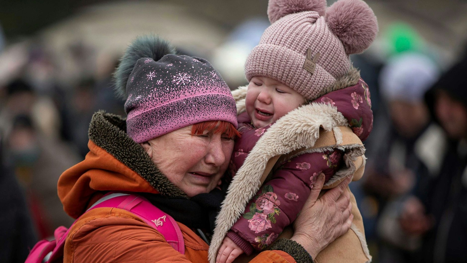 Eine weinende Frau mit einem Kind im Arm am Grenzübergang im polnischen Medyka.