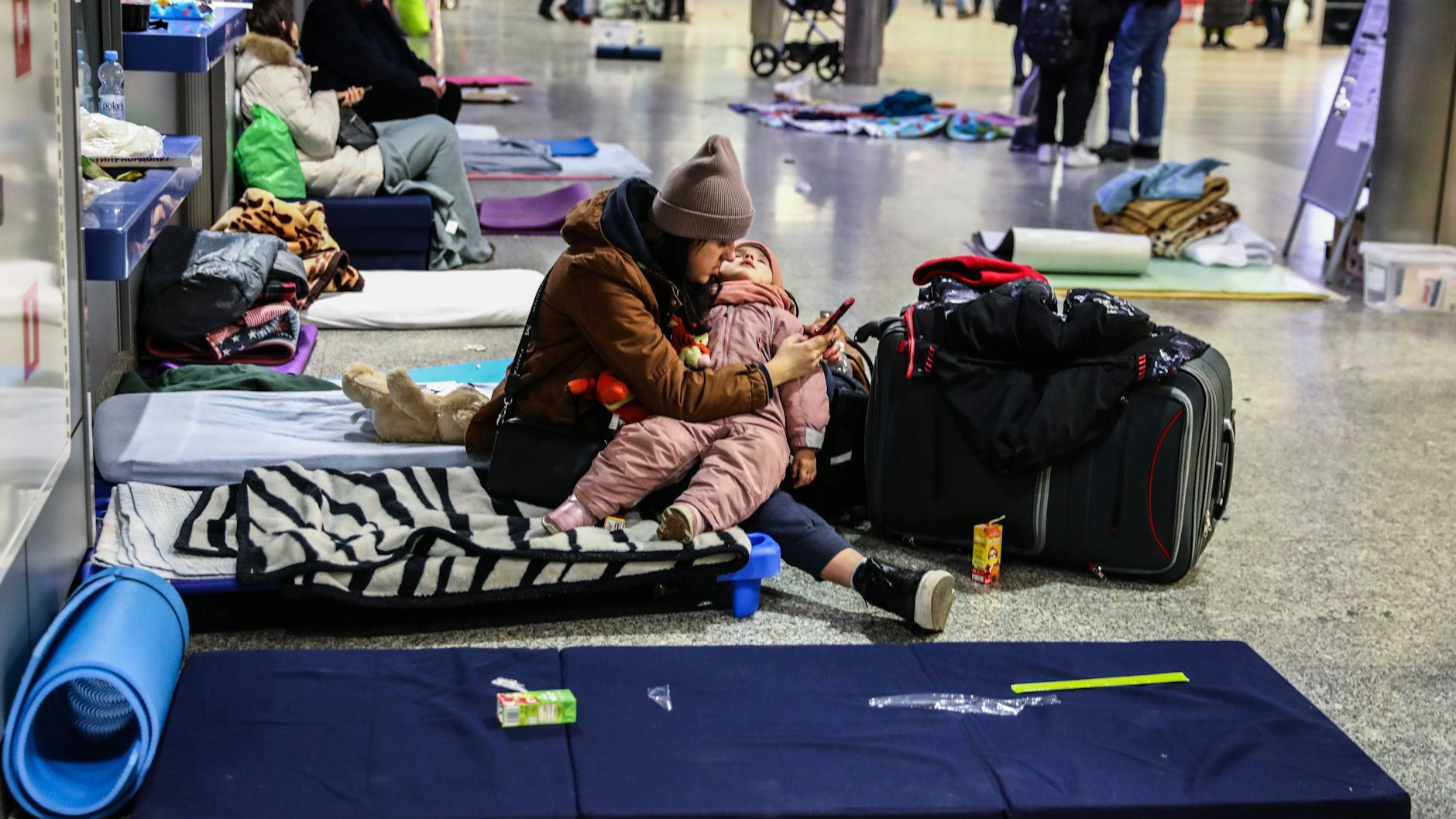 Eine ukrainische Frau hält ein schlafendes Kind - sie befinden sich im Hauptbahnhof der polnischen Stadt Krakow.