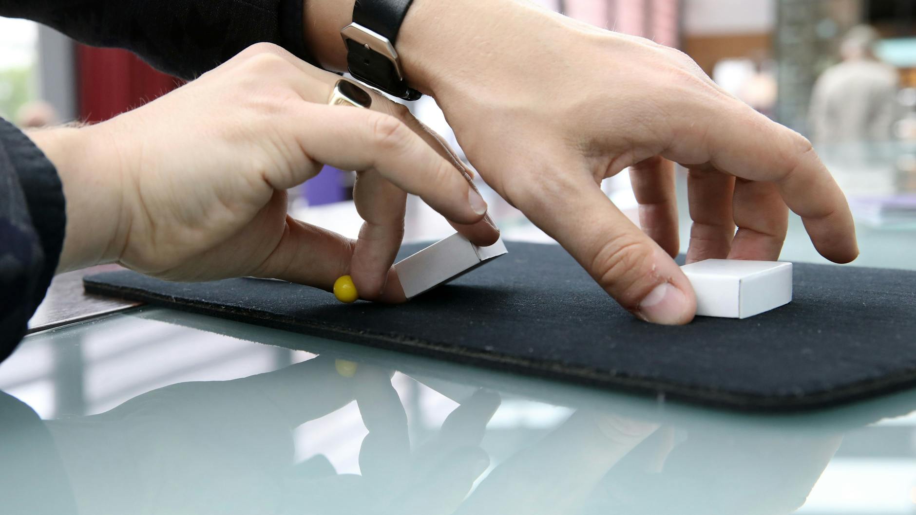 Dann heißt es, die Schachteln zu mischen. Der Spieler versteckt das kleine Kügelchen dabei zwischen den Fingern – die Zuschauer können es auch beim Mischen der drei Schächtelchen nicht sehen.