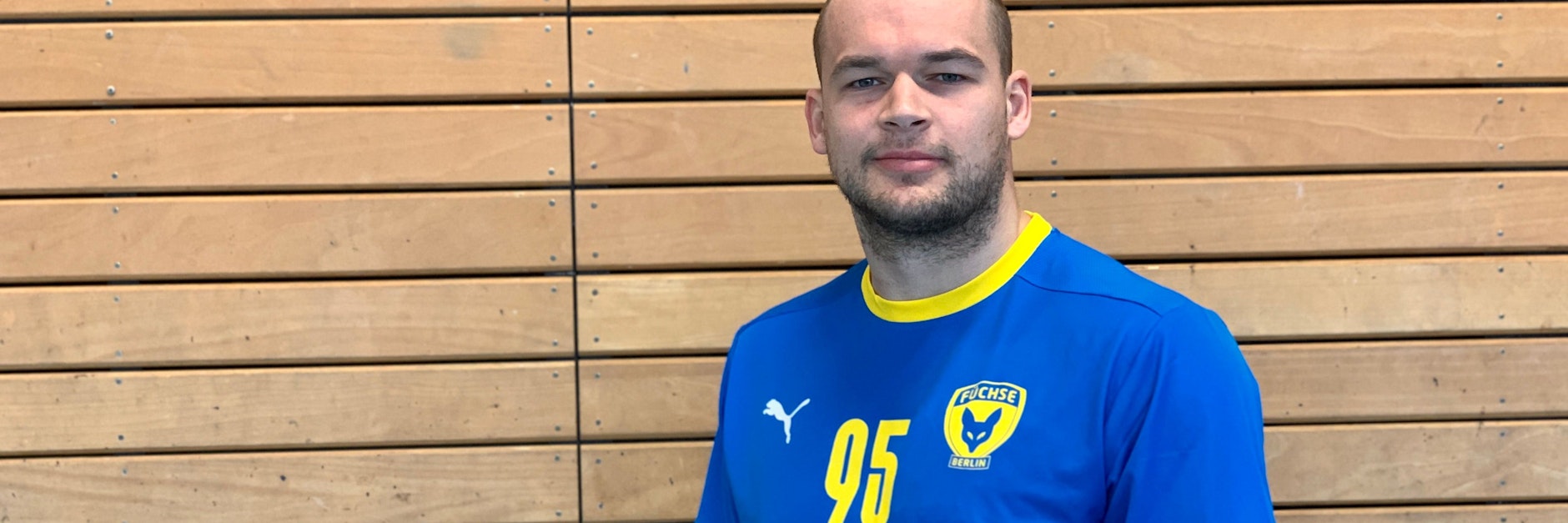 Füchse-Kapitän Paul Drux präsentiert schon mal das Sondertrikot in den Ukraine-Farben für das Spiel am Sonntag in Kiel.