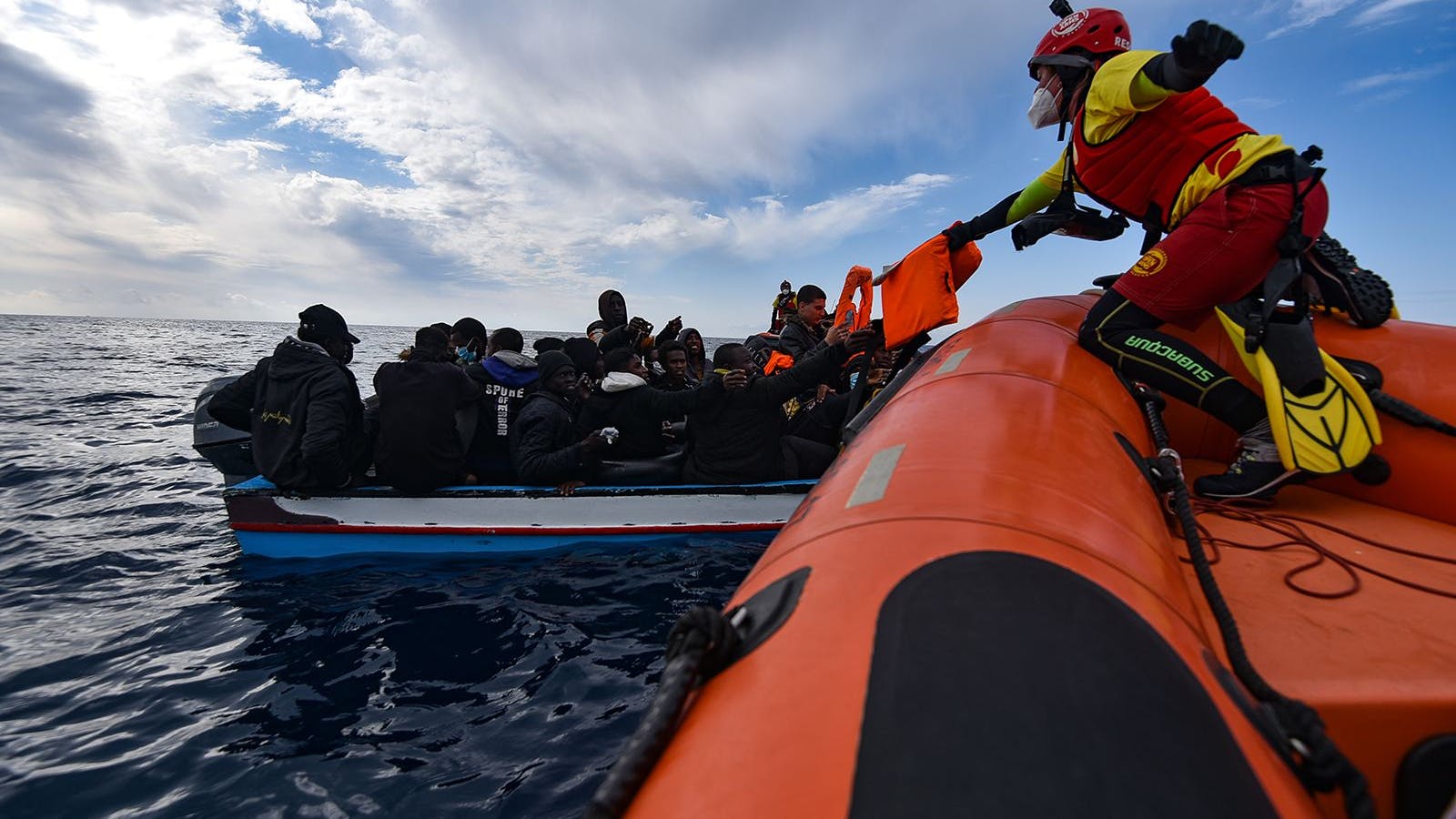 Mitglieder der NGO Open Arms helfen Migranten, die in einem Holzboot aufgebrochen sind (Archivbild). Viele Migranten sterben jährlich bei dem Versuch, übers Meer in die EU zu gelangen.