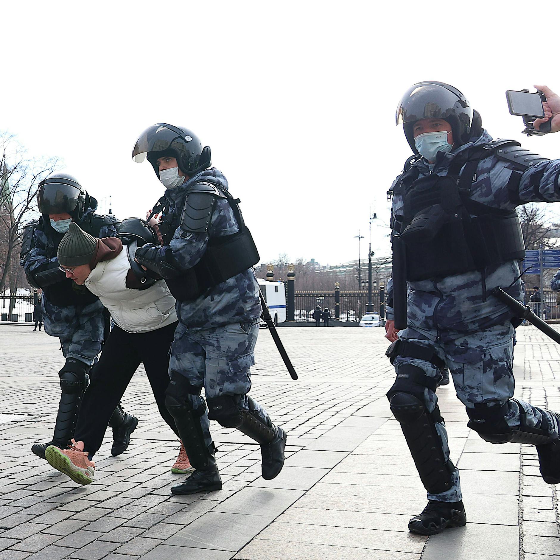 Proteste in Russland: Eine Frau hält ein weißes Schild hoch und wird abgeführt