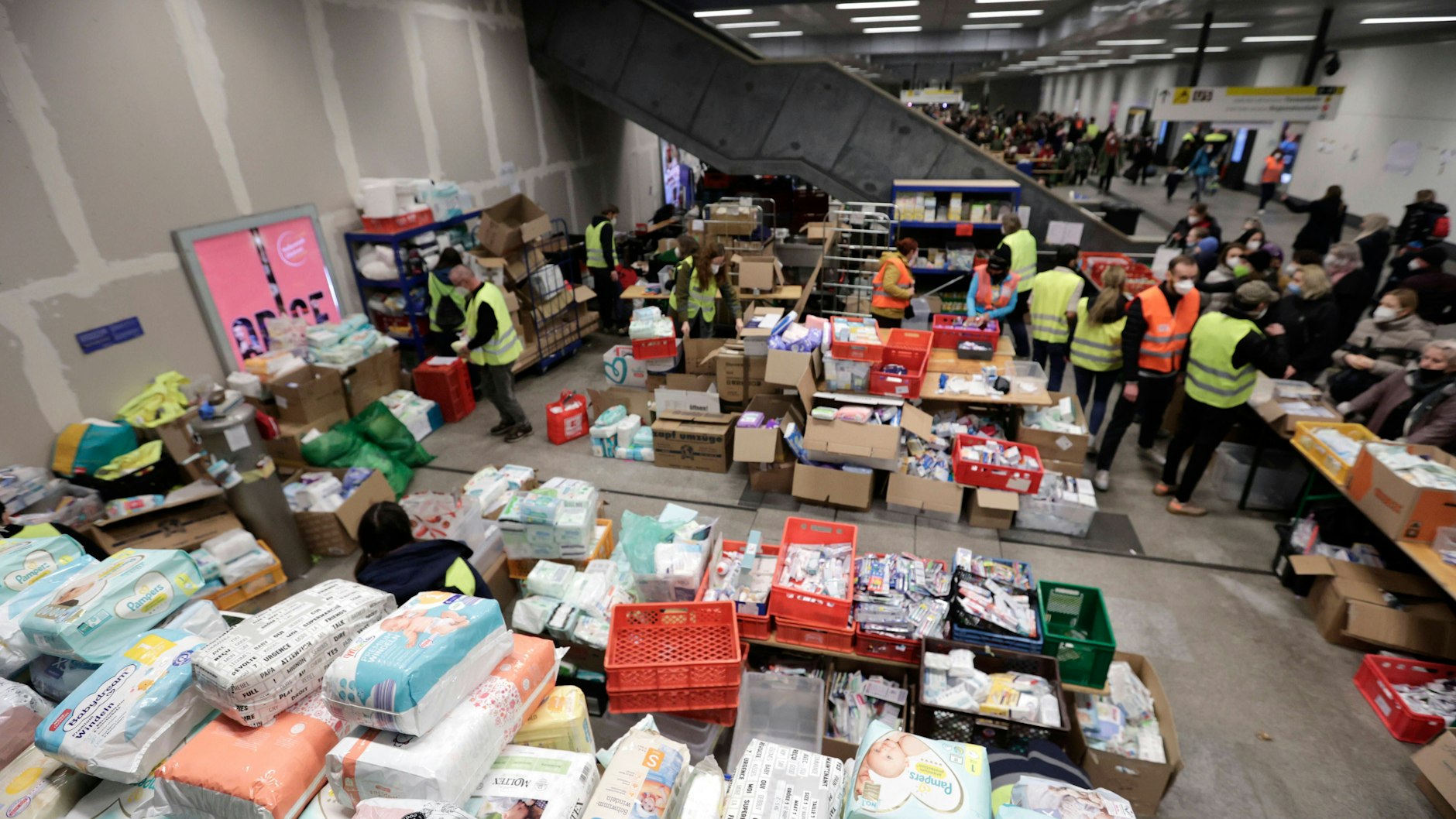 Ehrenamtliche geben im Untergeschoss des Berliner Hauptbahnhofs Spenden aus.