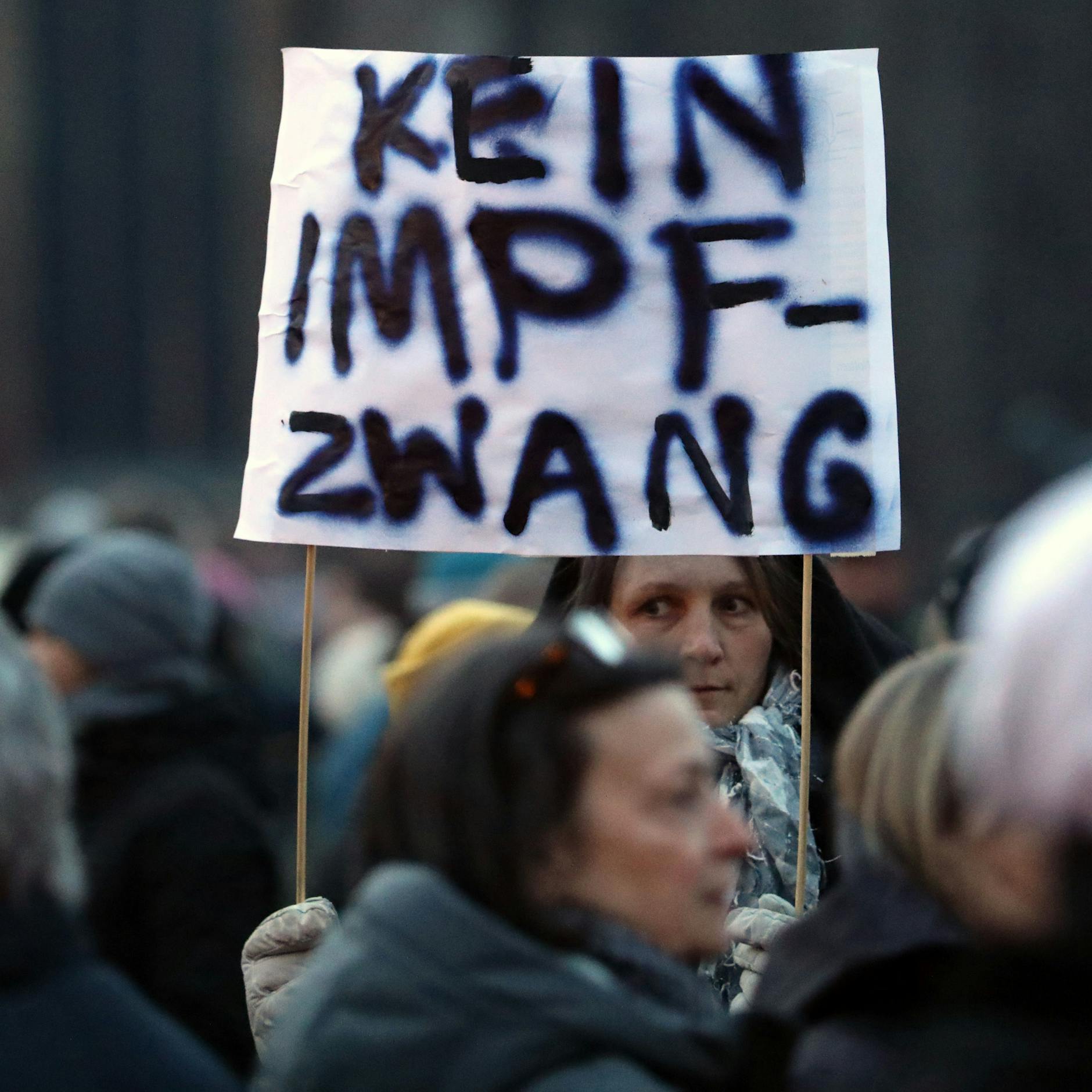 Teilnehmer einer Demonstration gegen Impfpflicht und Corona-Maßnahmen versammeln sich, auf einem Transparent steht „Kein Impfzwang“.