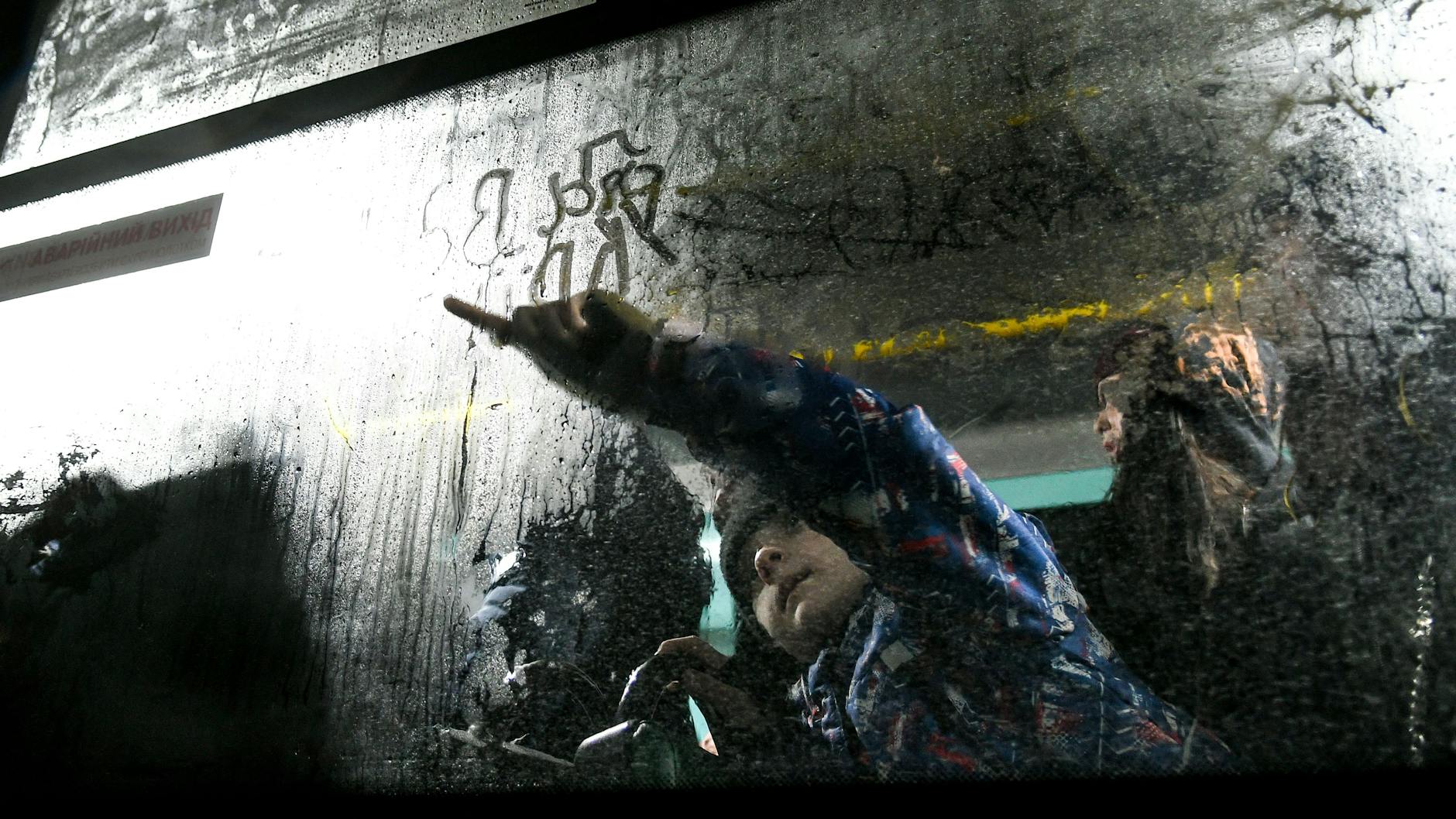 Ein Junge schreibt mit dem Finger auf einer beschlagenen Scheibe in einem Evakuierungsbus aus Enerhodar bei der Ankunft in Saporischschja im Südosten der Ukraine.