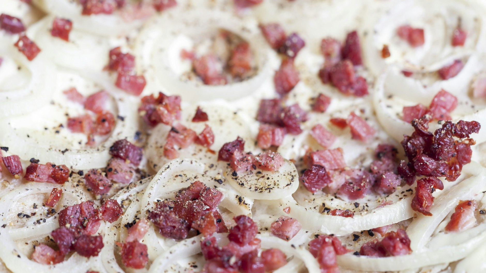 Mit Zwiebeln und Schinkenwürfeln wird der Flammkuchen perfekt. Mit dem Blumenkohlboden wird das Gericht zur leichten Alternative fürs Abendessen.