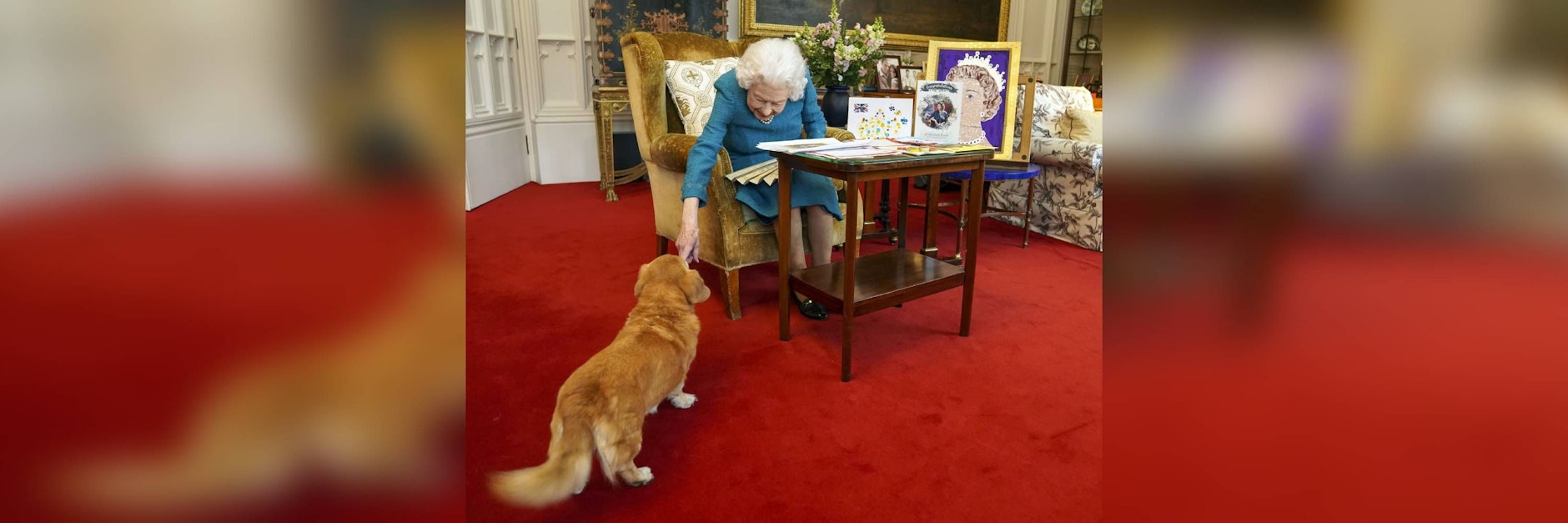 Die Queen streichelt einen ihrer Hunde.