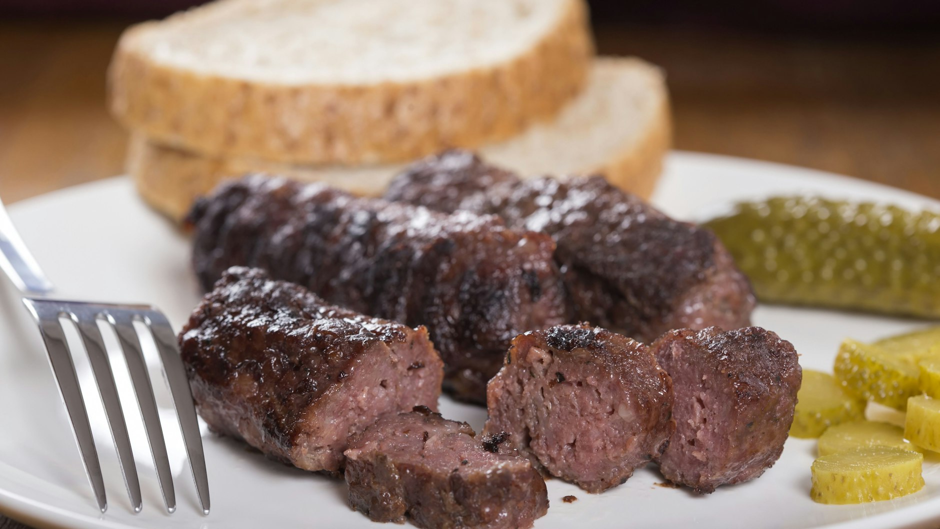 Leckere Mititei mit eingelegten Gurken und Brot auf dem Teller.