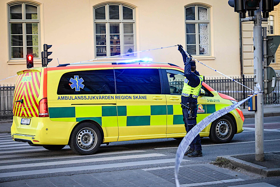 Ein Polizist lässt einen Rettungswagen hinter die Polizeiabsperrung, um Verletzte zu versorgen.