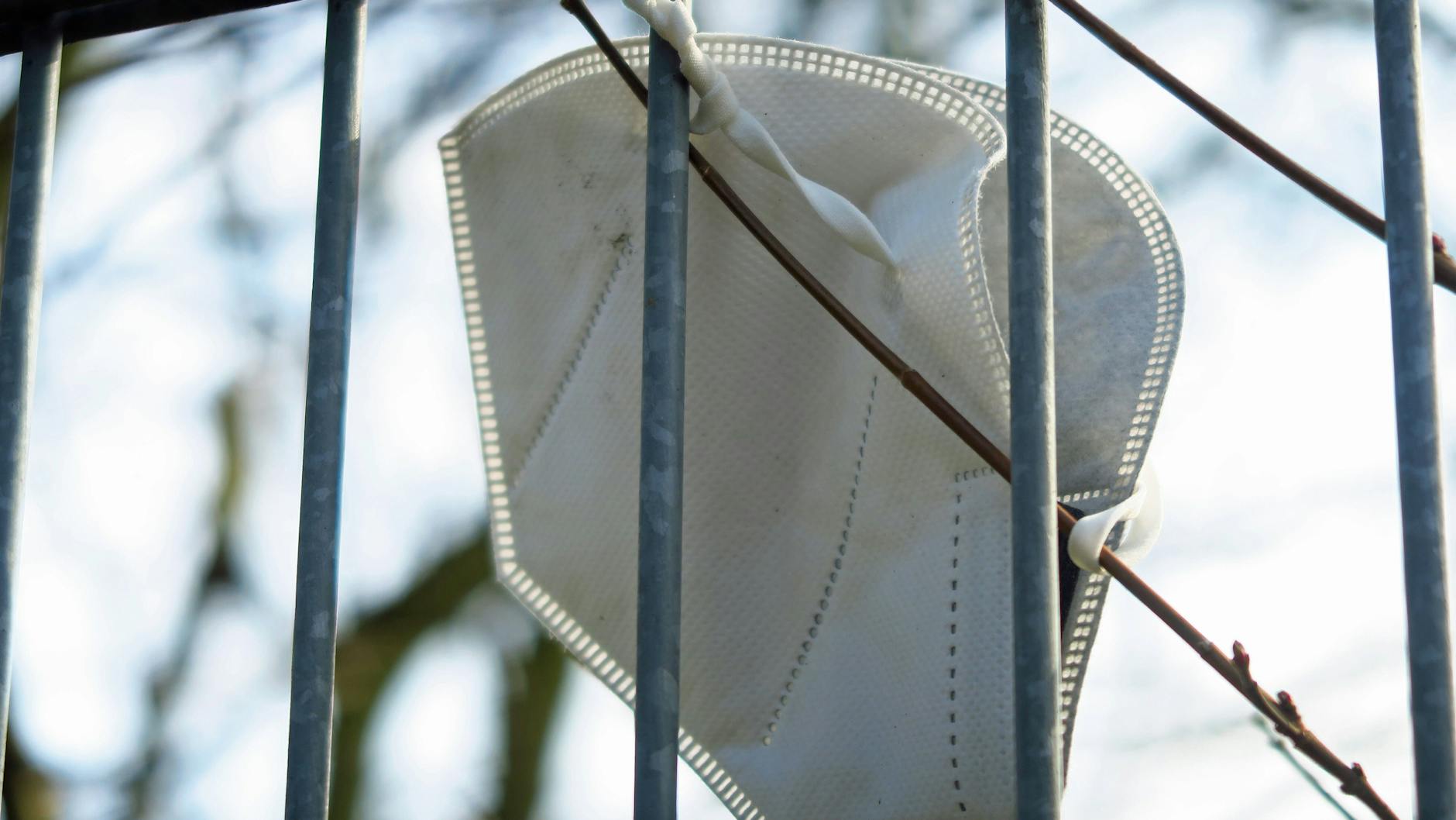 Eine FFP2-Maske hängt an einem Zaun.