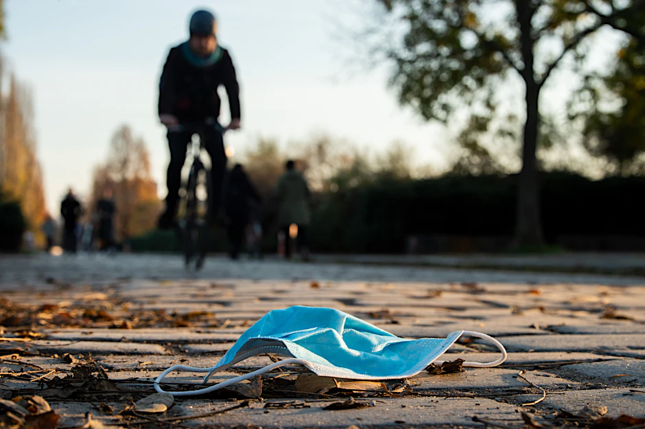 Auf einem Gehweg im Mauerpark Berlin liegt eine Maske auf dem Boden. Am ersten April fällt die Maskenpflicht in Berliner Schulen. Doch sollen die Schüler weiterhin zum freiwilligen Tragen der Maske ermutigt werden.