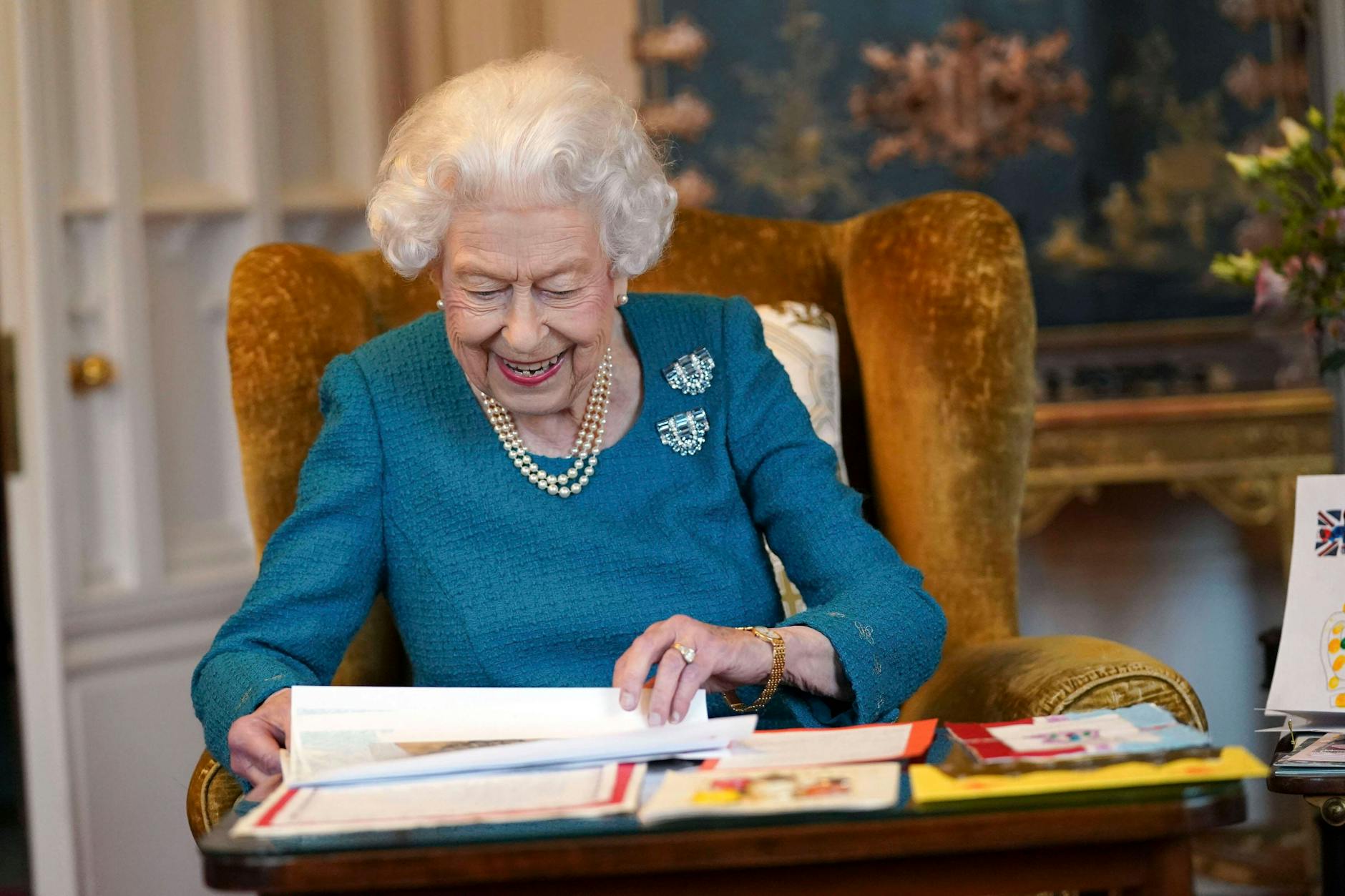 Queen Elizabeth II. sichtet Glückwunschkarten zum Platinjubiläum auf Schloss Windsor. Aber warum trägt sie zweimal die gleiche Brosche?