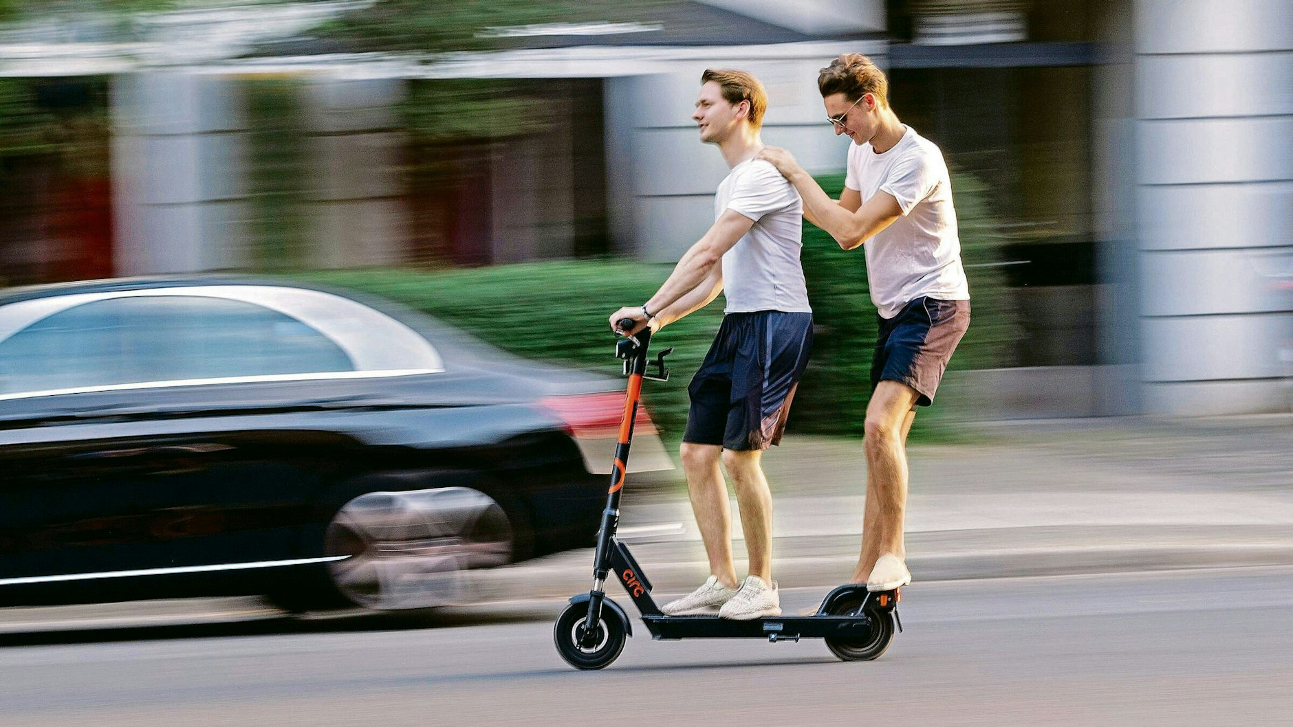 Spaß auf der Straße: zwei junge Männer mit dem E-Scooter unterwegs in Berlin