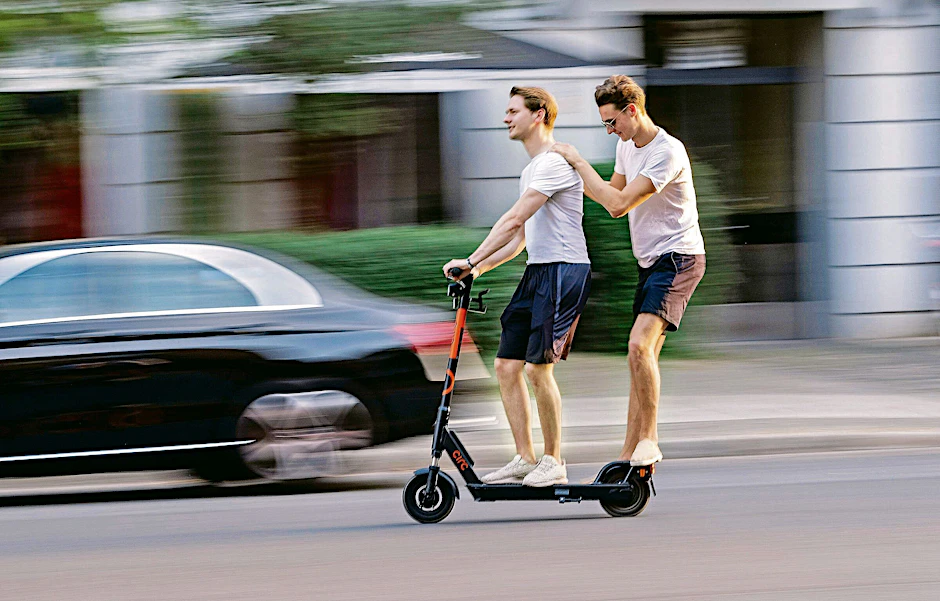 Spaß auf der Straße: zwei junge Männer mit dem E-Scooter unterwegs in Berlin