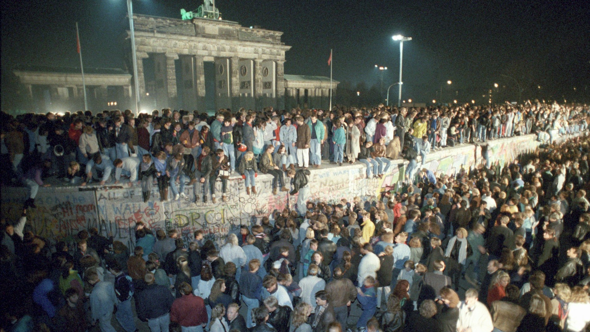 Menschen auf der Berliner Mauer vor dem Brandenburger Tor in der Nacht vom 9. auf den 10. November 1989.&nbsp;