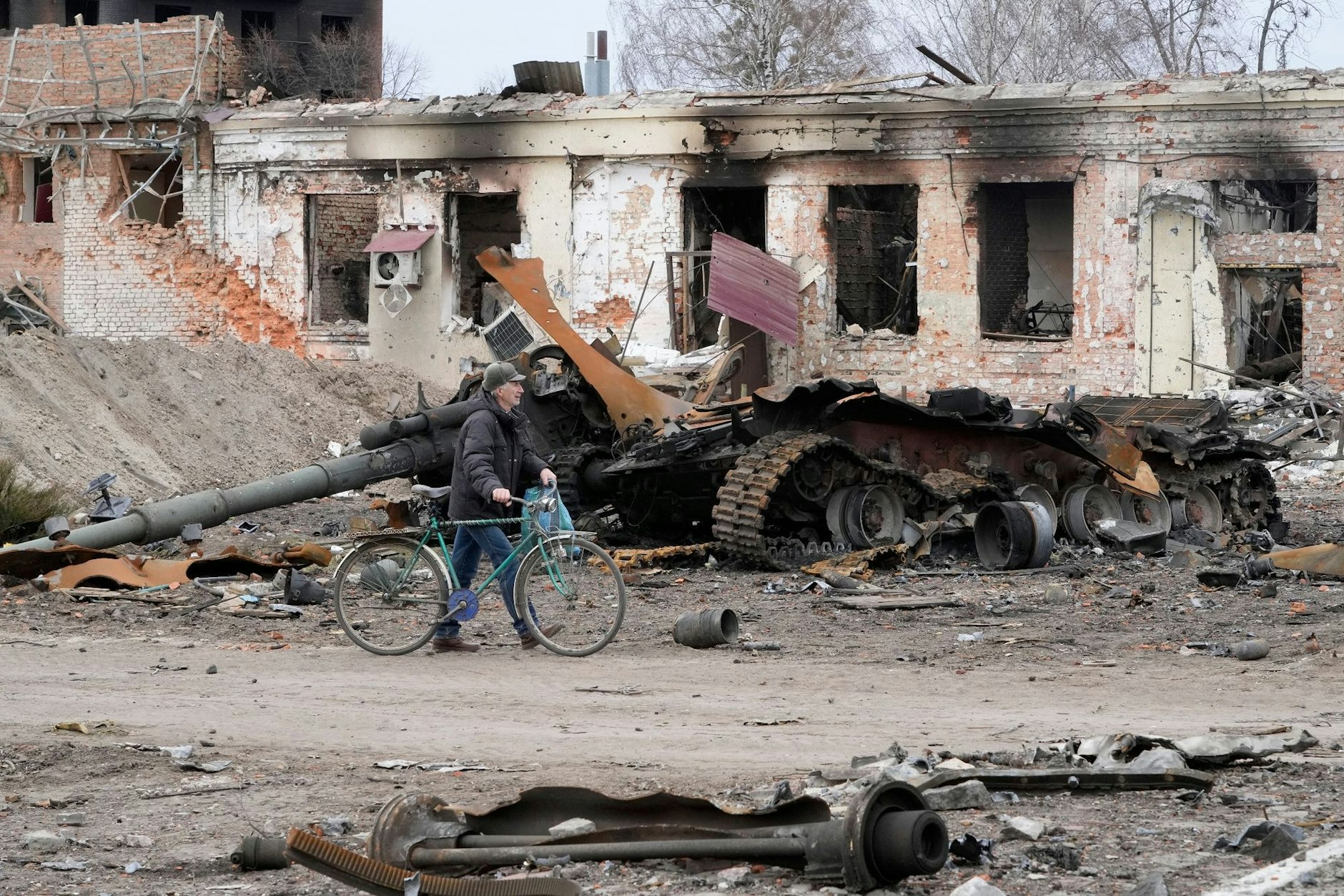 Ein Anwohner geht mit seinem Fahrrad in Trostjanez rund 400 km östlich von Kiew vor beschädigten Gebäuden und einem zerstörten Panzer entlang.