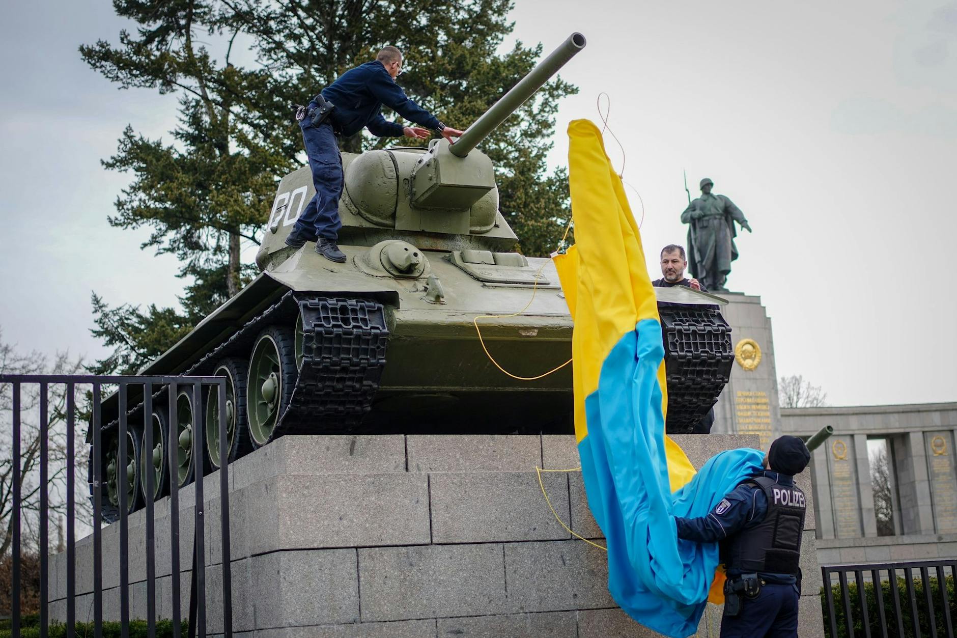 Polizeibeamte entfernen die Flagge der Ukraine von einem historischen Panzer am Sowjetischen Ehrenmal an der Straße des 17. Juni. Ein Verdacht auf eine Straftat liegt in diesem Fall laut Polizei nicht vor.