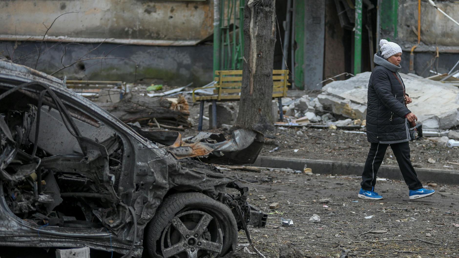 Eine Frau geht an den Trümmern eines Autos im Stadtteil Soltavka in Charkiw, Ukraine, vorbei.