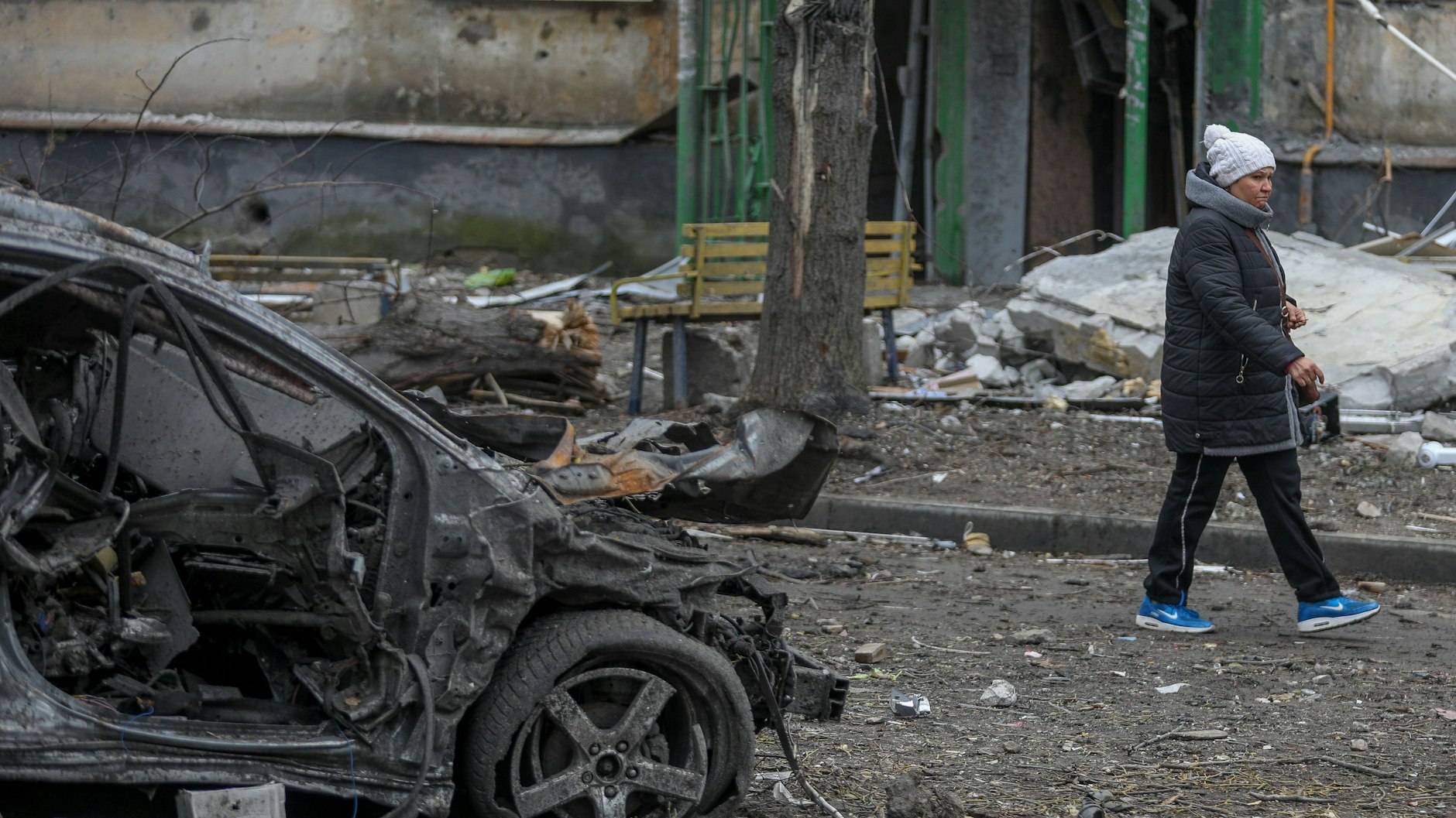 Eine Frau geht an den Trümmern eines Autos im Stadtteil Soltavka in Charkiw, Ukraine, vorbei. 