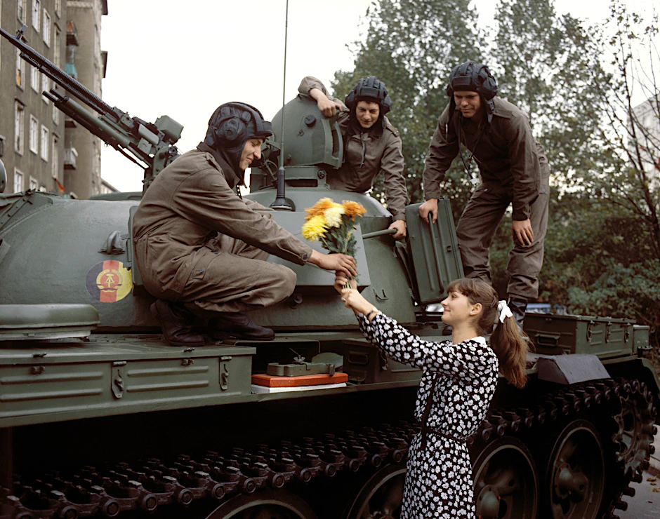 Eine junge Frau überreicht einem Soldaten Blumen während der letzten Militärparade der DDR im Oktober 1989.