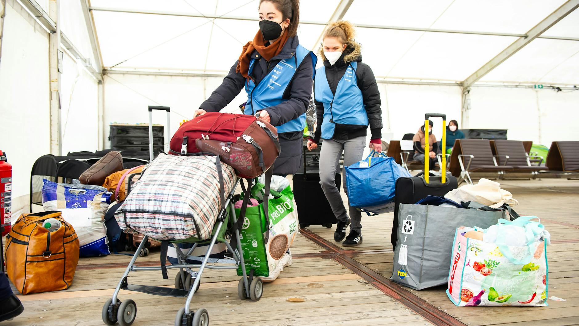 <a target="_blank" href="https://service.berlin.de/standort/330887">Freiwillige Helferinnen transportieren im Ankunftszentrum TXL Gepäck.</a>