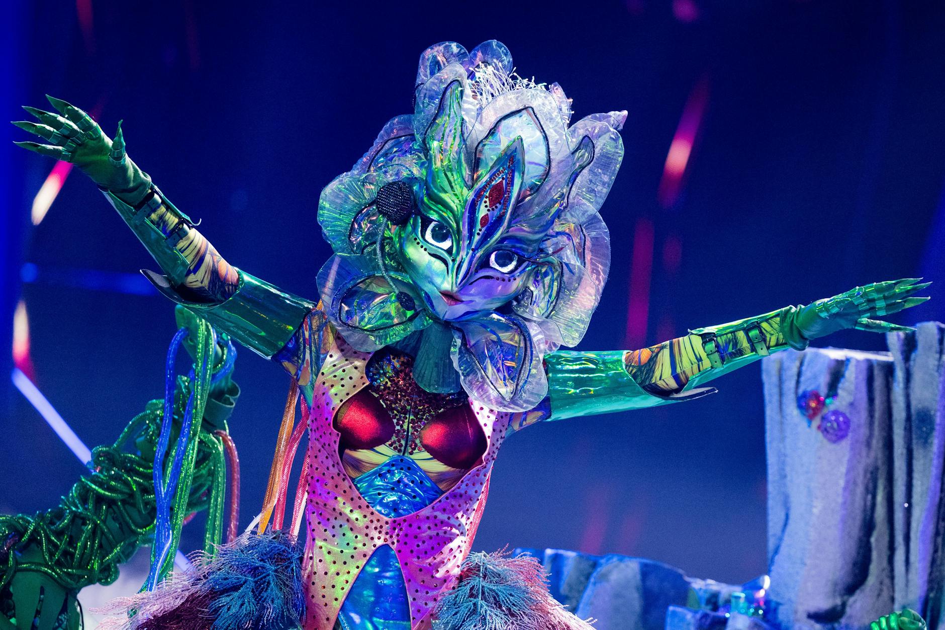 Galax'sis auf der Bühne von The Masked Singer. Ihre Tänzer führen sie an den grünen Ranken über die Bühne.
