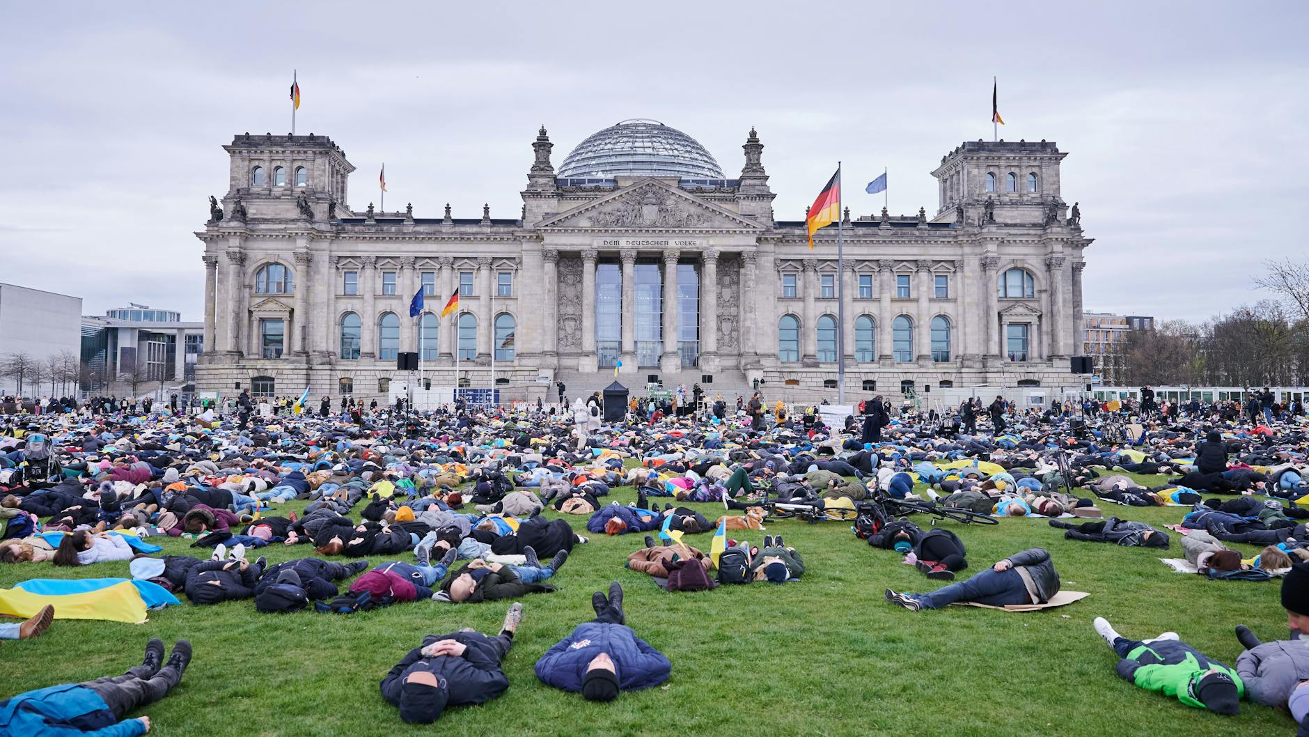 Demonstranten liegen auf der Wiese vor dem Reichstagsgebäude. Sie demonstrieren gegen den Angriff auf die Ukraine und für ein Energie-Embargo gegen Russland.