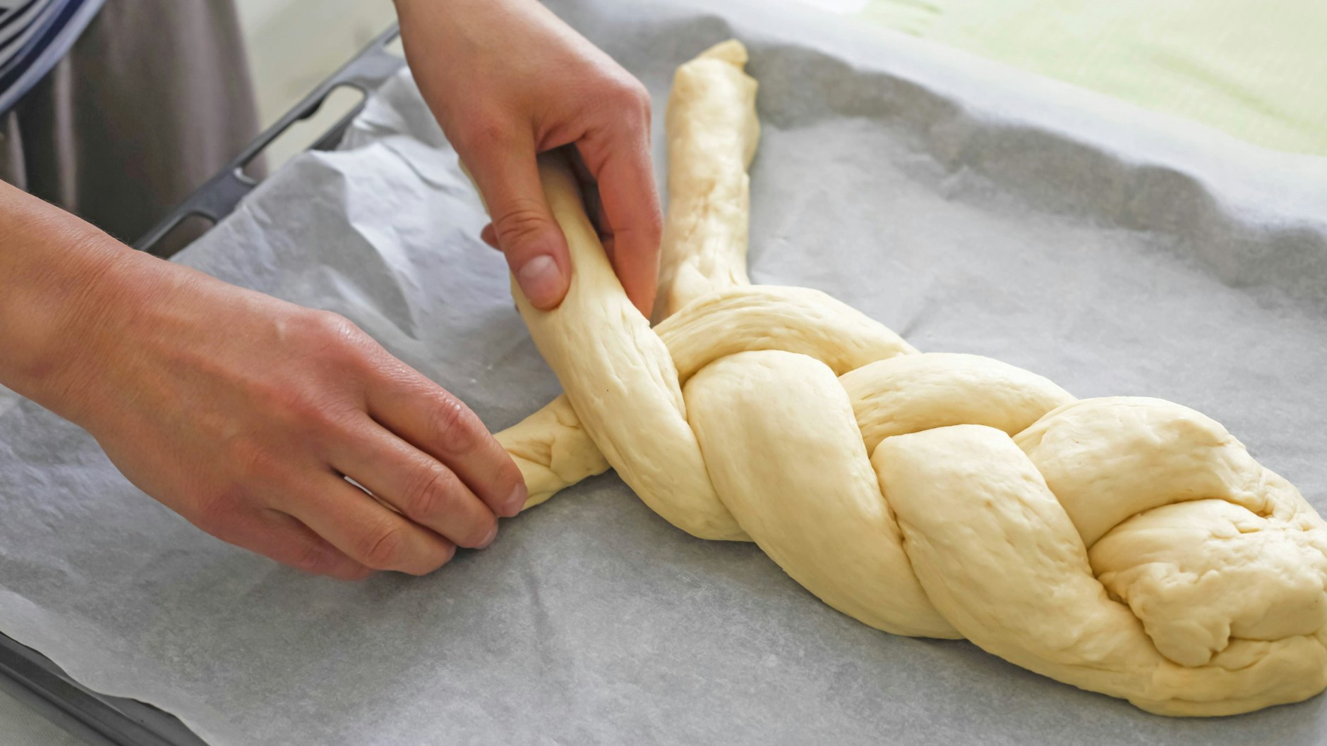 Die drei Teigstränge werden so zu einem Zopf geflochten.