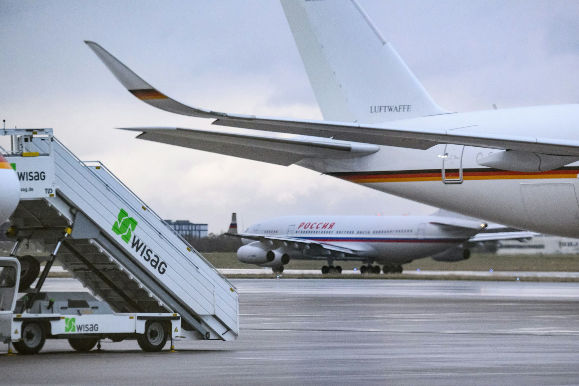 Im Hintergrund sieht man die russische Maschine, die die Diplomaten nach Hause holte.