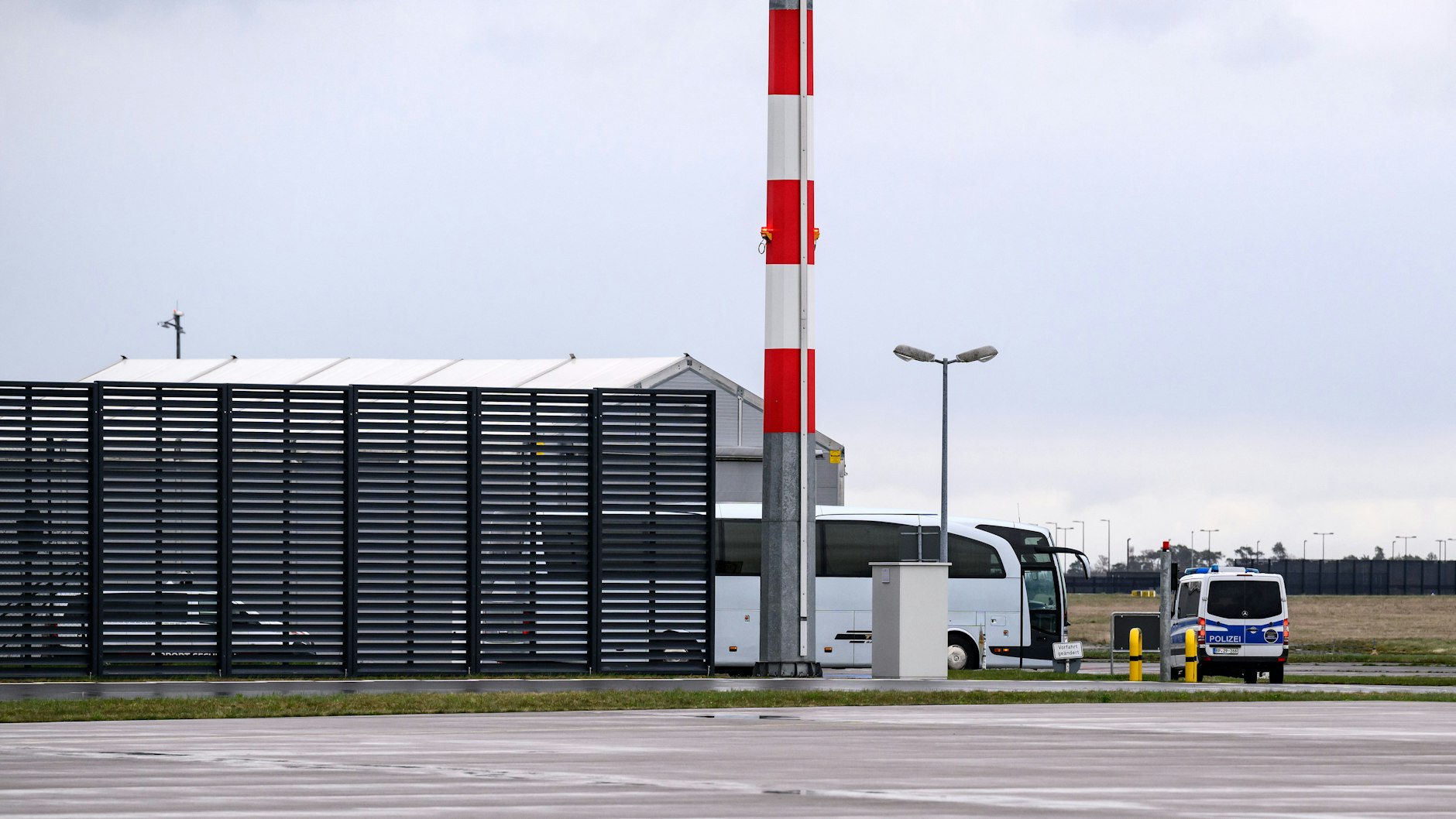 Ein Reisebus mit russischen Botschaftsmitarbeitern wird von Polizeifahrzeugen auf dem Flughafen Berlin Brandenburg eskortiert.