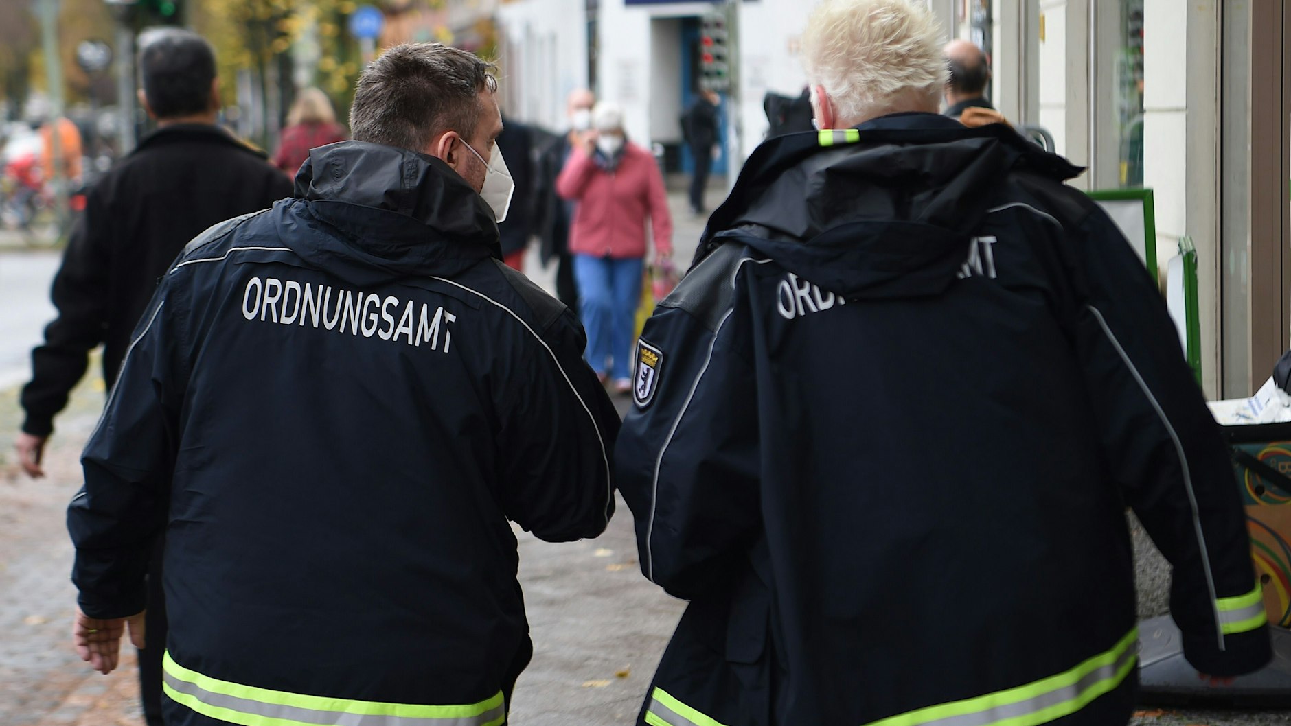 Mitarbeiter und Mitarbeiterinnen vom Ordnungsamt kontrollieren eine Straße in Berlin.