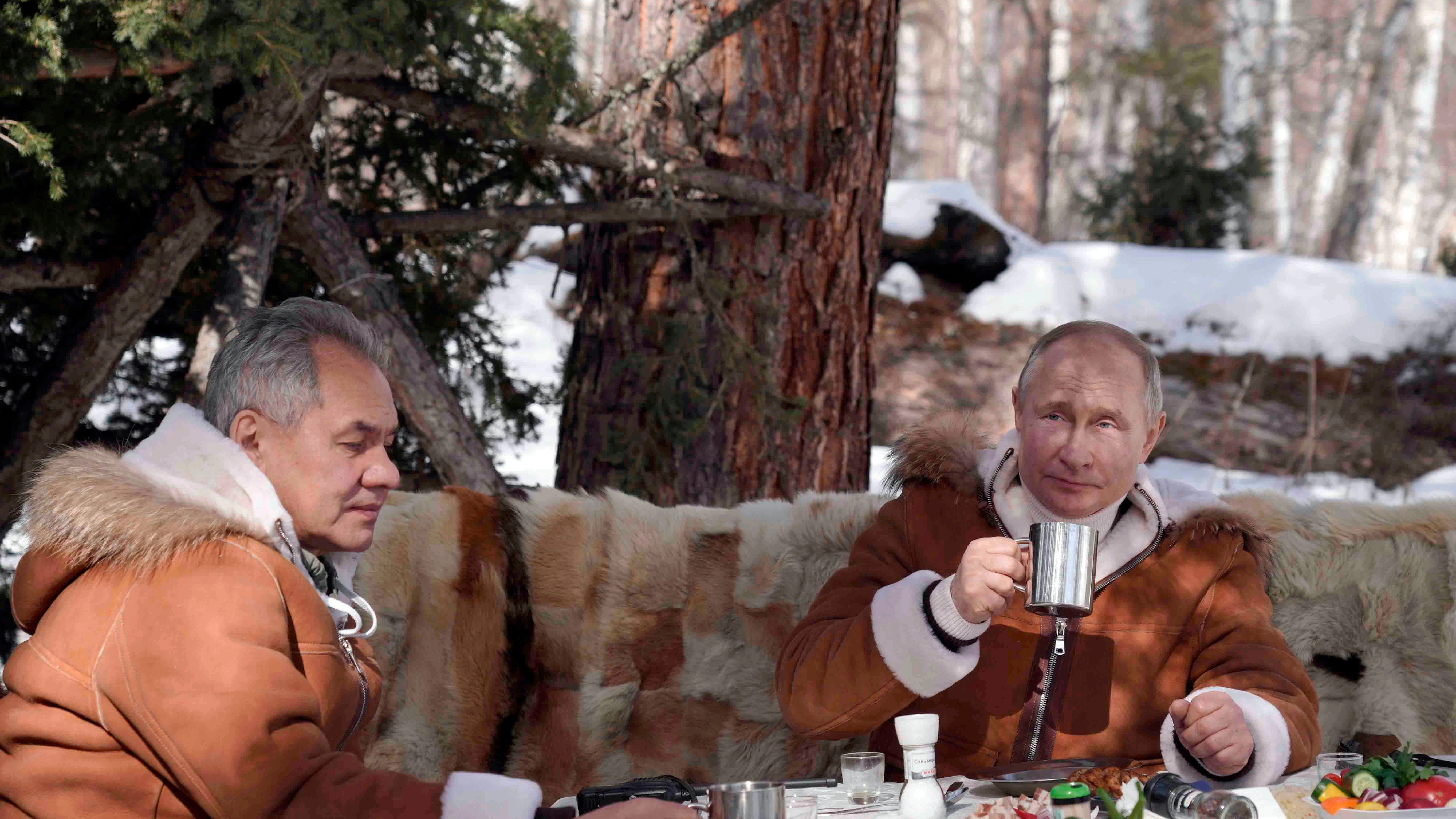 Wladimir Putin (r.), Präsident von Russland, isst und trinkt zusammen mit Sergej Schoigu, Verteidigungsminister von Russland, in einem Taigawald in der sibirischen Region in Russland.