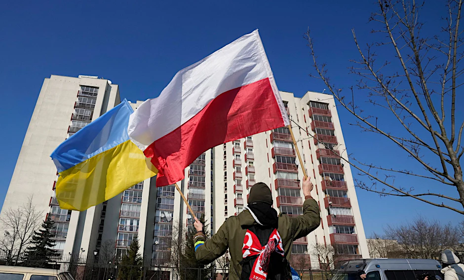 Ein Mann schwenkt während einer Demonstration in Warschau die ukrainische und die polnische Flagge vor einem Gebäude, in dem russische Diplomaten untergebracht sind. 