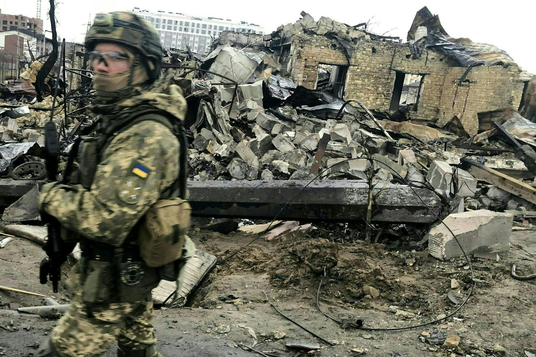 Ein ukrainischer Soldat läuft in Butscha an den Trümmern zerstörter Häusern vorbei. 