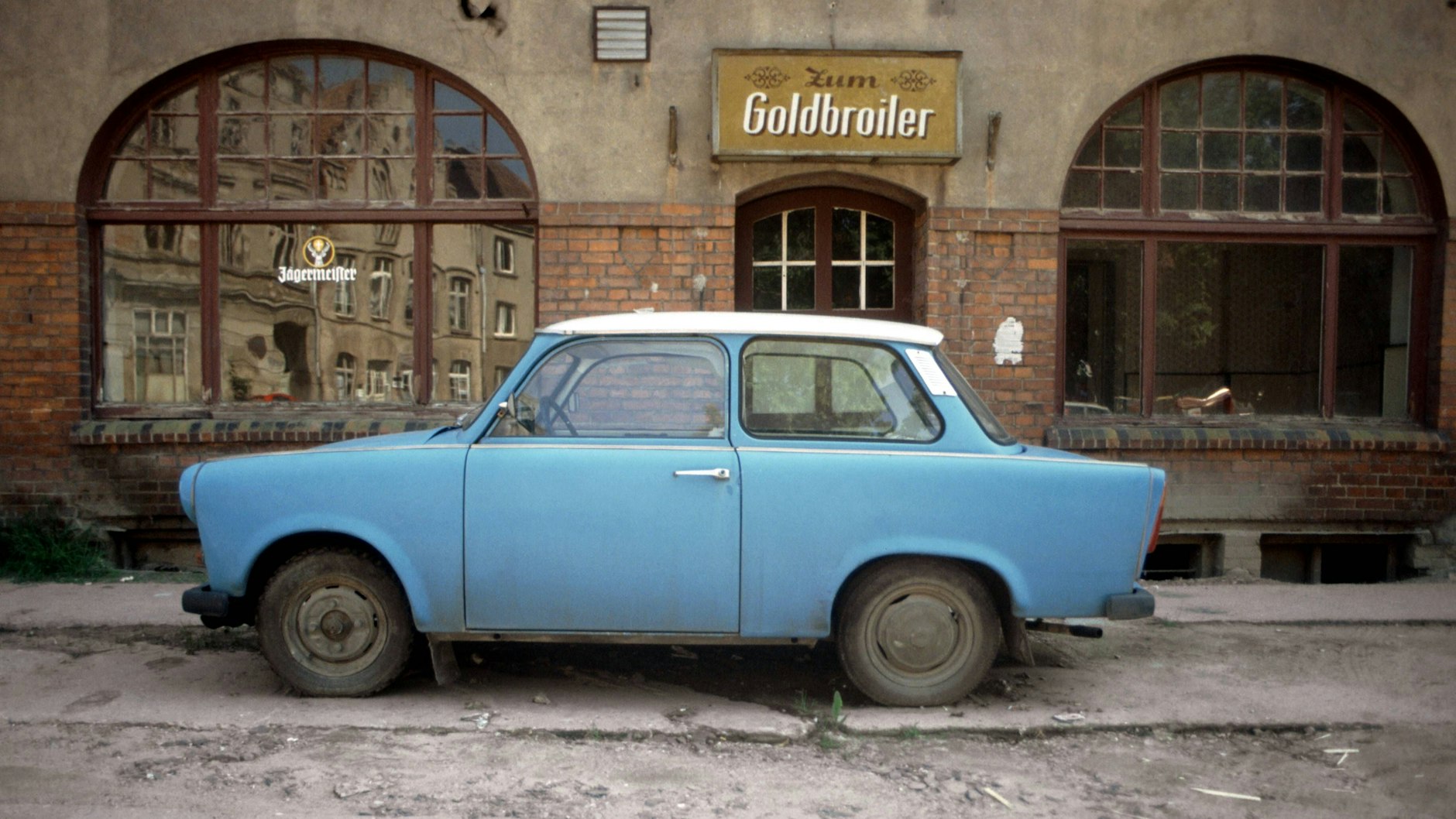 Die Restaurants Zum Goldbroiler gab es überall in der DDR. Hier steht kurz nach der Wende ein blauer Trabant vor dem Restaurant in Wismar.