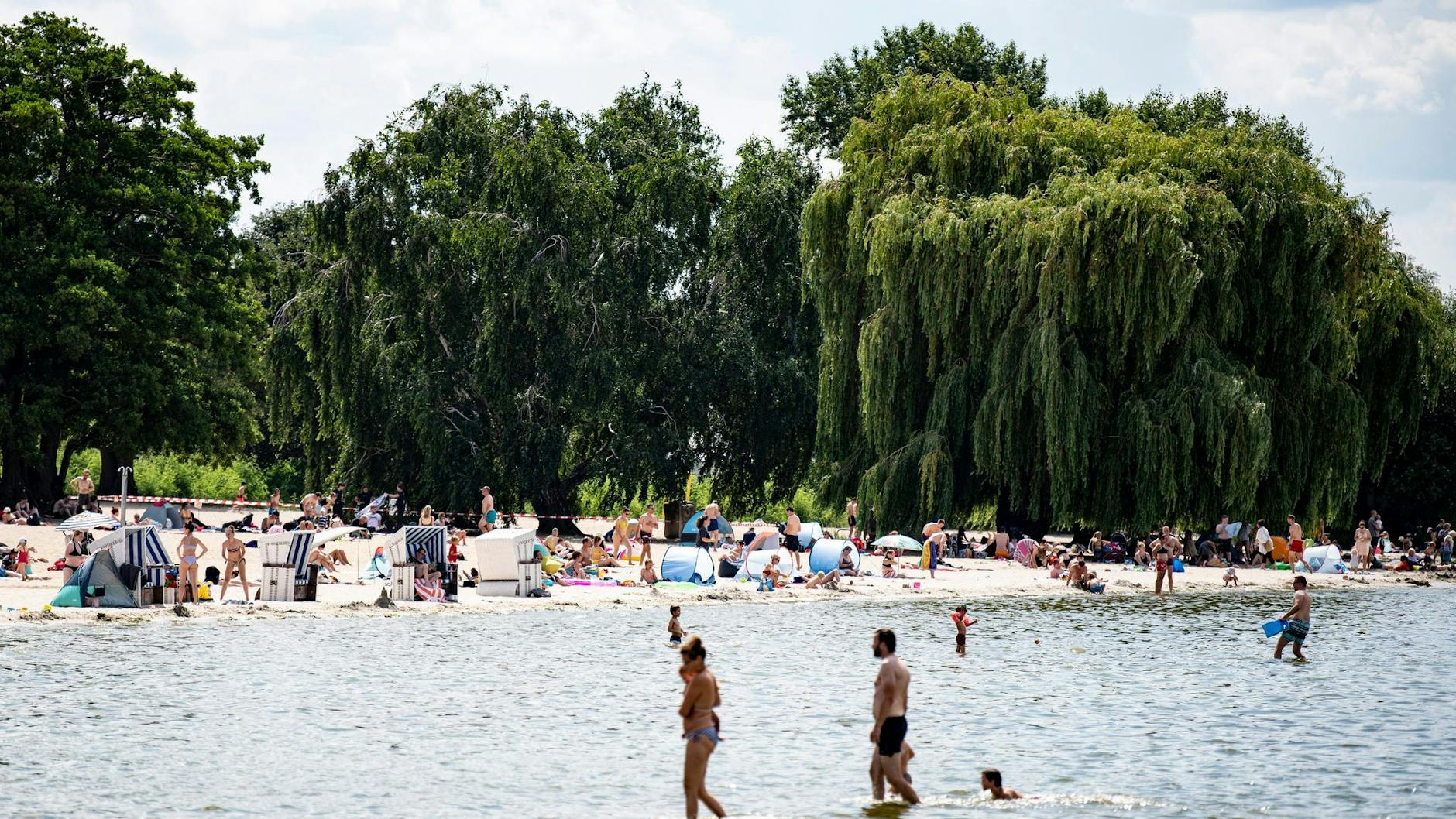Besucher des Strandbades am Wannsee genießen das sonnige Wetter am Wasser.