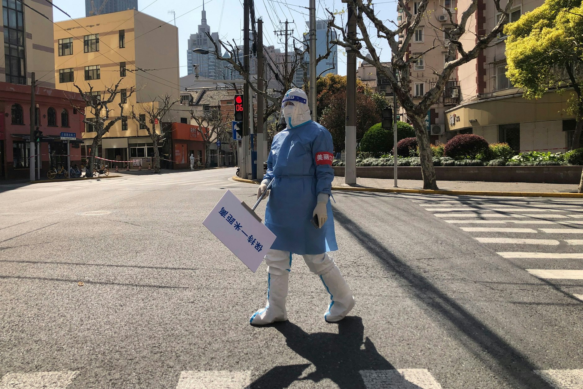 Eine Stadt hielt den Atem an: In menschenleerem Schanghai hält ein Gesundheitsmitarbeiter ein Schild, das zum Einhalten der 1-Meter-Abstandsregel erinnert.