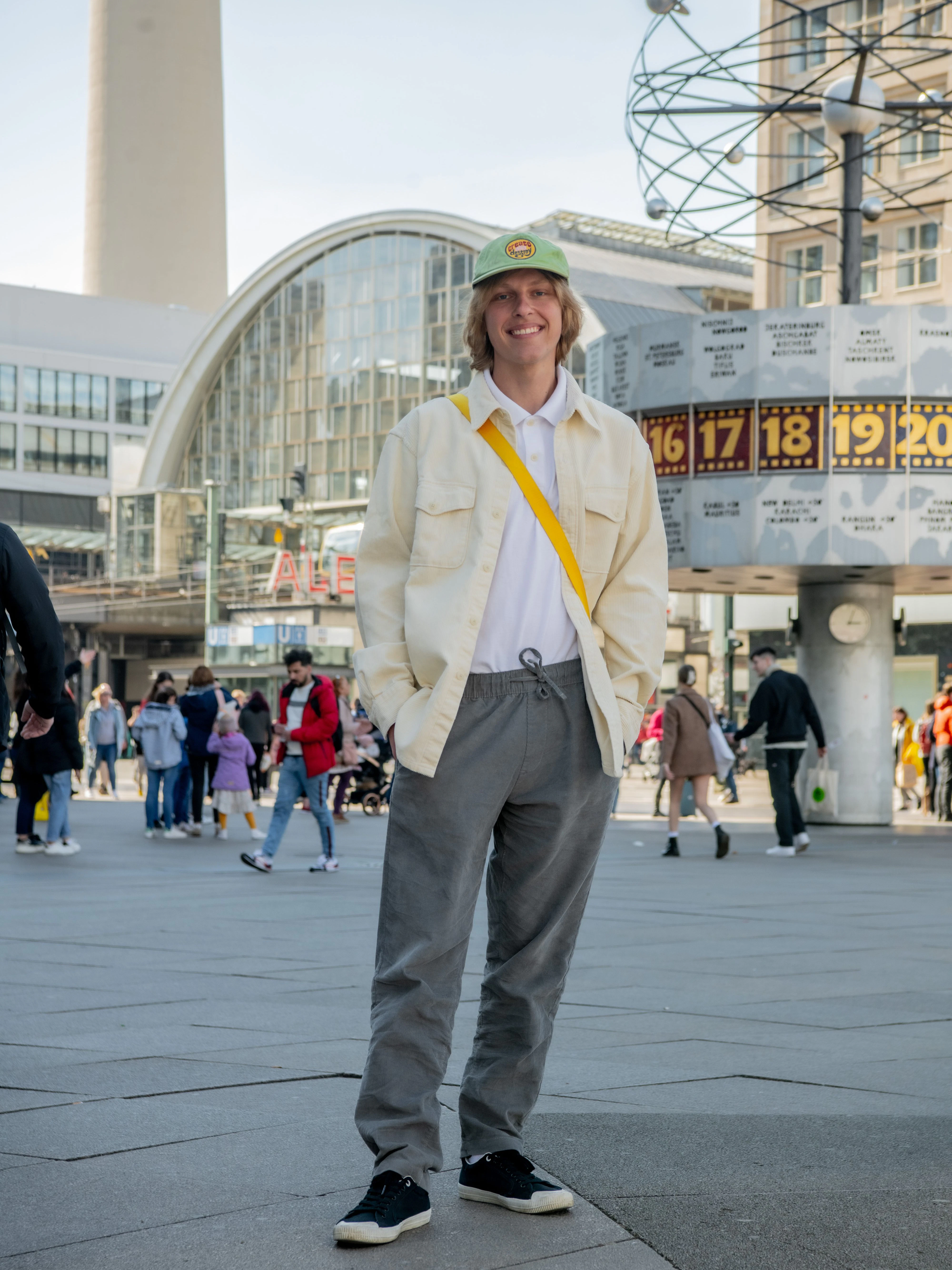 Der Musiker Seba ist aus Los Angeles angereist, um seine ukrainische Oma zu besuchen, die nach der Flucht bei einer deutschen Familie in Potsdam untergekommen ist. Ein trauriger Anlass für eine Familienzusammenkunft, aber eine herzerwärmende Geschichte. Seba ist auch Skater, der Kenner sieht es am casual Look: cremeweiße Cordjacke (Uniqlo), weißes Poloshirt (Target), graue Cordhose (Onia) und leichte Stoffschuhe (Replay). Im Hintergrund zu sehen: die Weltzeituhr, die hier seit 1969 steht.