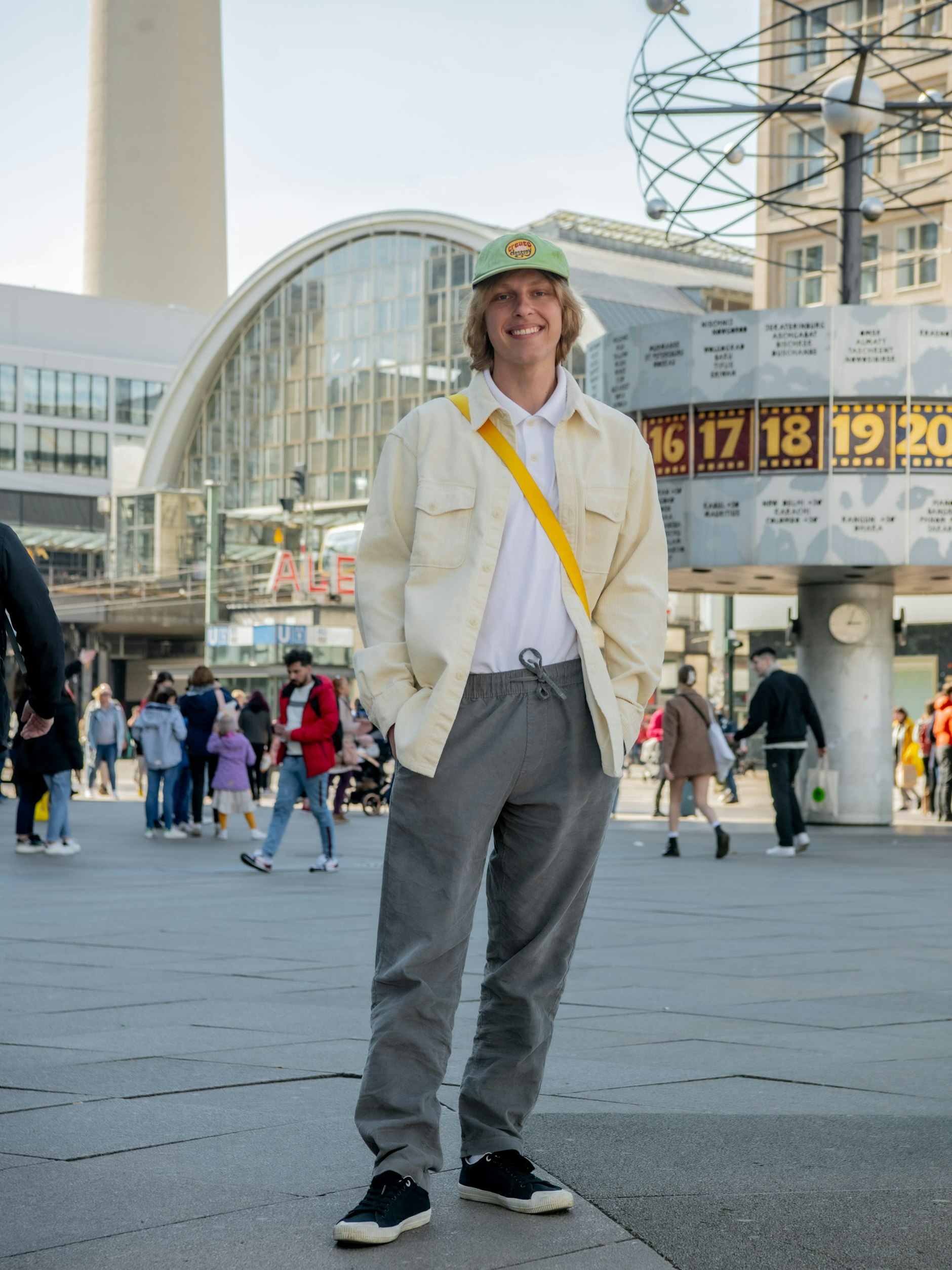 Der Musiker Seba ist aus Los Angeles angereist, um seine ukrainische Oma zu besuchen, die nach der Flucht bei einer deutschen Familie in Potsdam untergekommen ist. Ein trauriger Anlass für eine Familienzusammenkunft, aber eine herzerwärmende Geschichte. Seba ist auch Skater, der Kenner sieht es am casual Look: cremeweiße Cordjacke (Uniqlo), weißes Poloshirt (Target), graue Cordhose (Onia) und leichte Stoffschuhe (Replay). Im Hintergrund zu sehen: die Weltzeituhr, die hier seit 1969 steht.