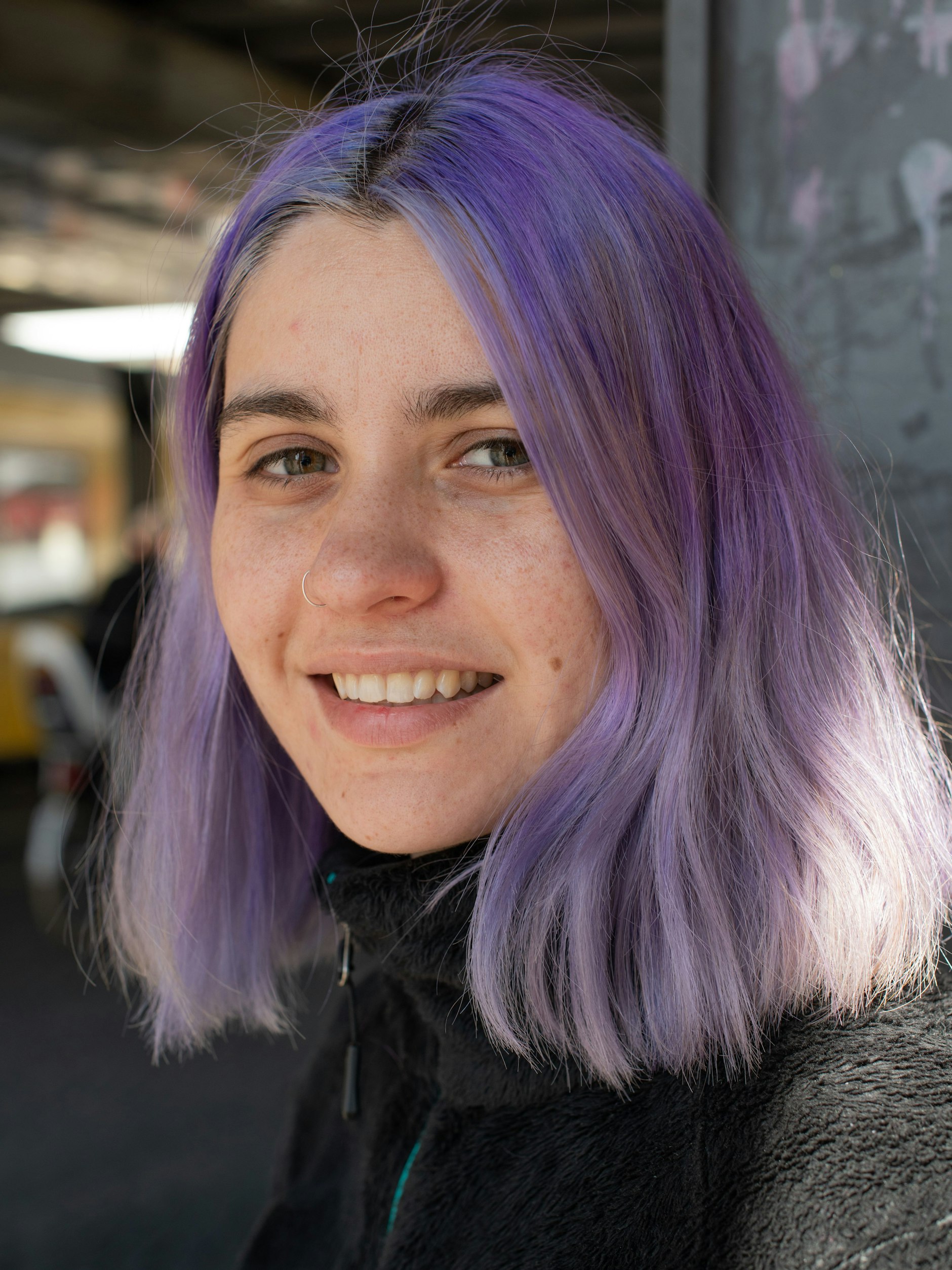 Raxide trägt gerne knallige Farben auf dem Kopf. Derzeit ist es ein pastelliges Violett. Dazu kombiniert sie ein schlichtes Outfit in Schwarz, bestehend aus Teddy-Jacke von The North Face, Uniqlo-Hose und Reebok-Sneakers. Dazu eine Crossbody-Bag der Outdoor-Marke Patagonia.