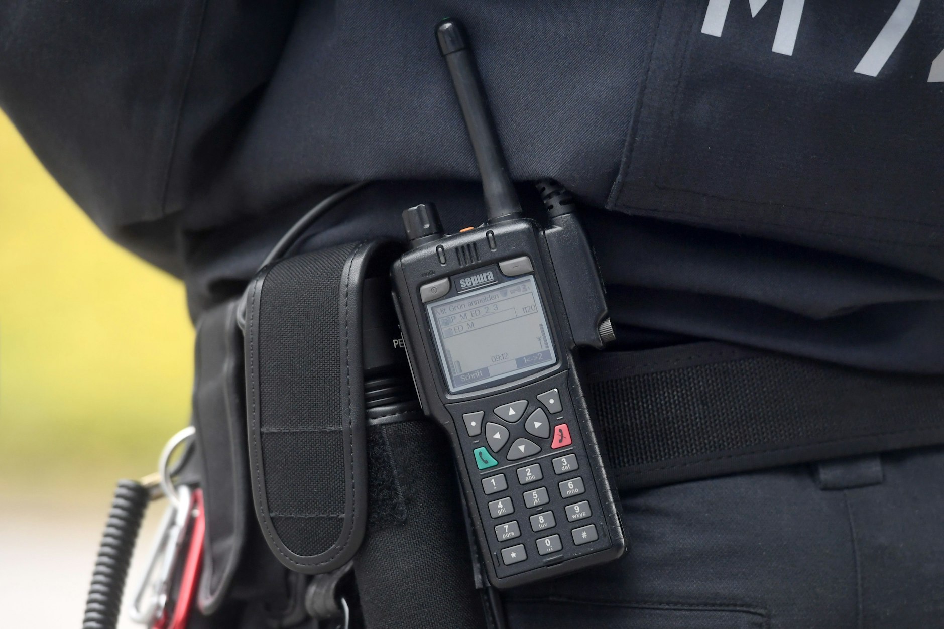 Eine Polizistin trägt ein digitales Polizei-Funkgerät am Gürtel.