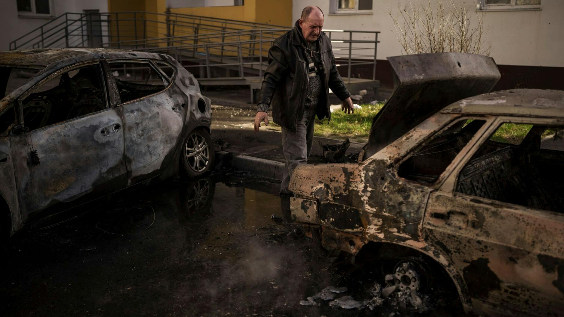 Ein Mann begutachtet sein verbranntes Auto nach einem russischen Angriff in Charkiw.