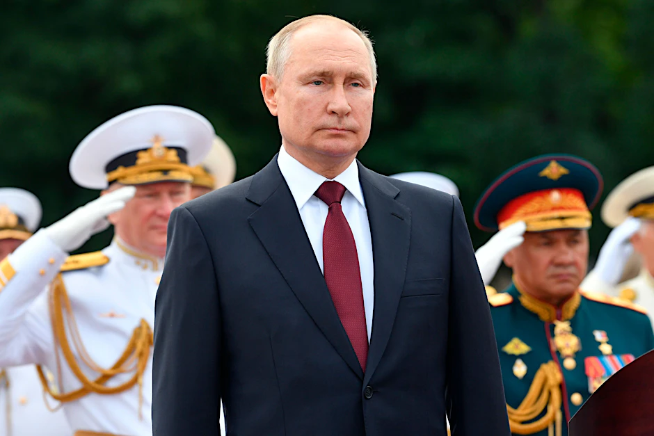 Wladimir Putin (M.), Präsident von Russland, hält seine Rede, während Admiral Nikolai Jewmenow (l.), Oberbefehlshaber der russischen Marine, und Sergej Schoigu (r.), Verteidigungsminister von Russland, bei einer Parade zum Tag der Marine salutieren. Ein Bild aus dem Jahr 2021.