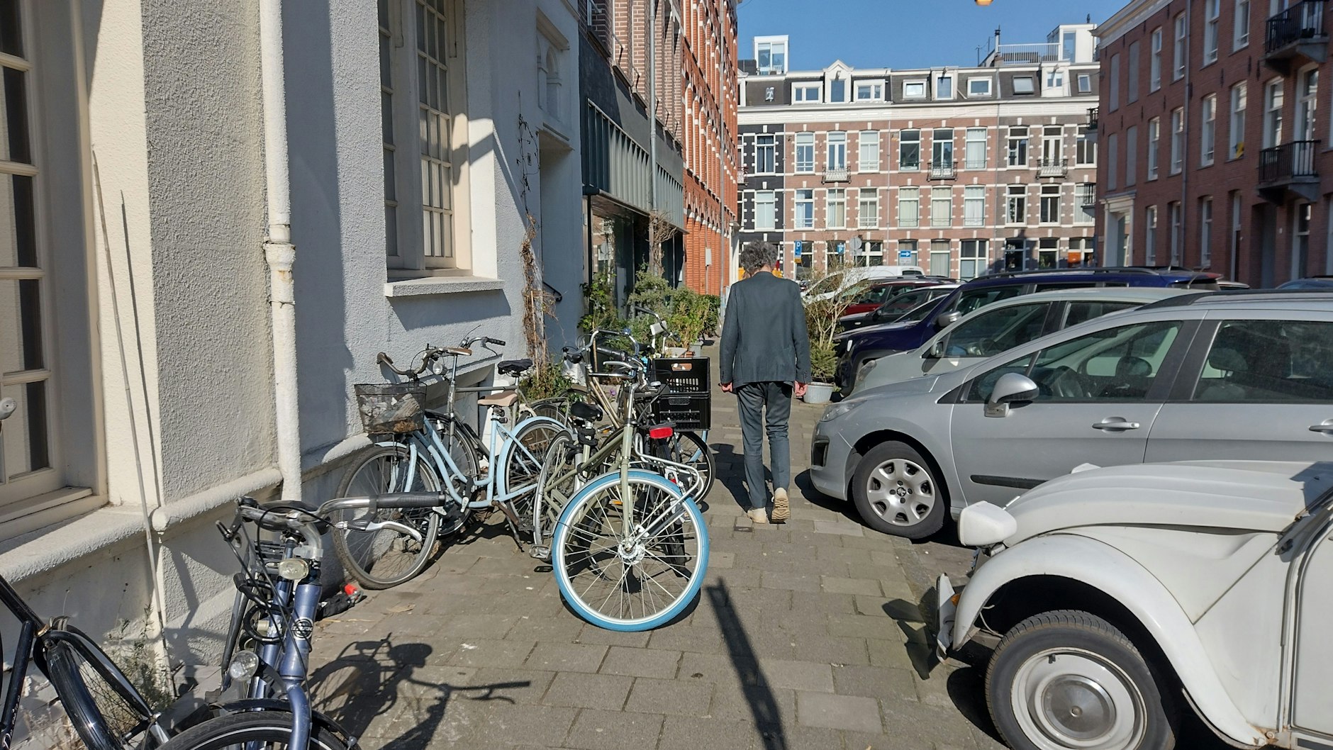 Fahrräder und Autos machen Fußgängern den Platz streitig. Eine typische Gehwegszene in Amsterdam.