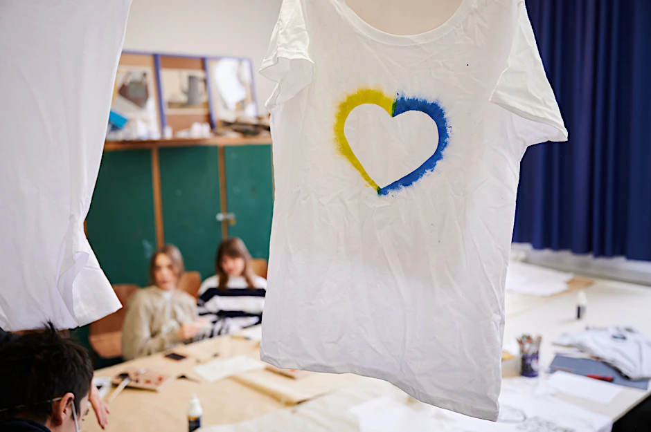 Ein T-Shirt mit einem Herz in den Farben der Ukraine hängt im Klassenraum einer Willkommensklasse am Willi-Graf-Gymnasium in Lichterfelde.