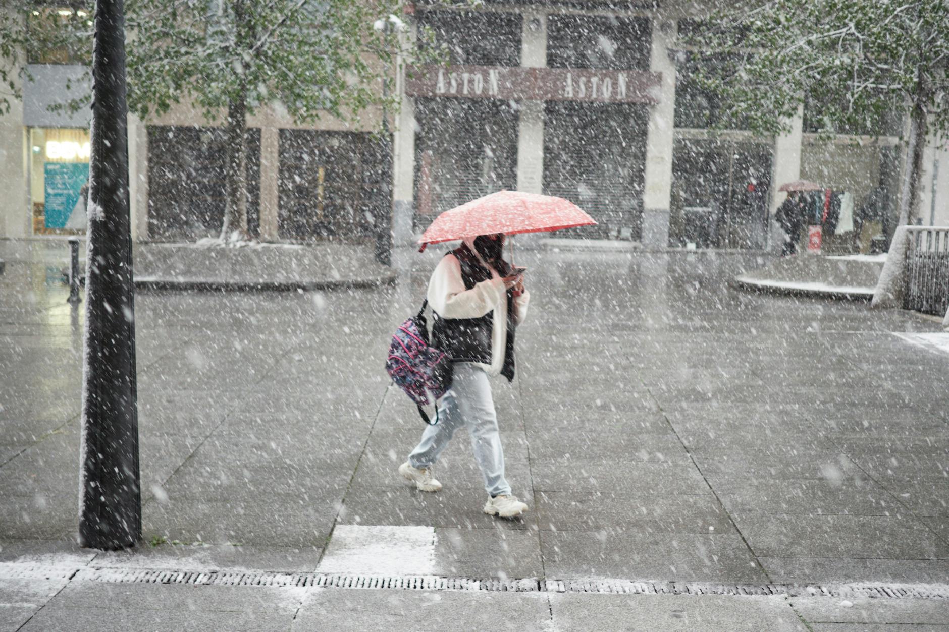 Eine Frau läuft bei dichtem Schneefall durch die spanische Stadt Pamplona.