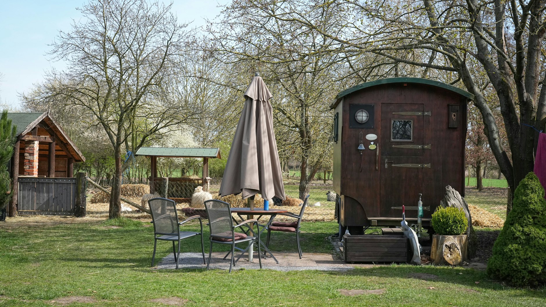 Zum Wagen gehören ein Sonnenschirm, Tisch und Stühle davor.