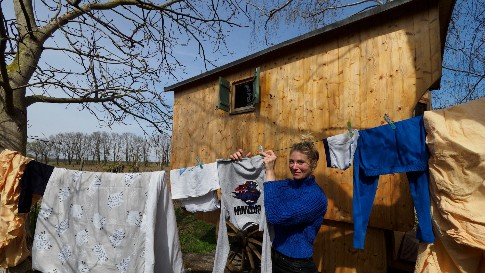 Die Berliner Urlauberin Claudia Kleiner hängt auf dem „Erlenhof“ neben ihrem Schäferwagen „Schäfchenglück“ Wäsche auf.