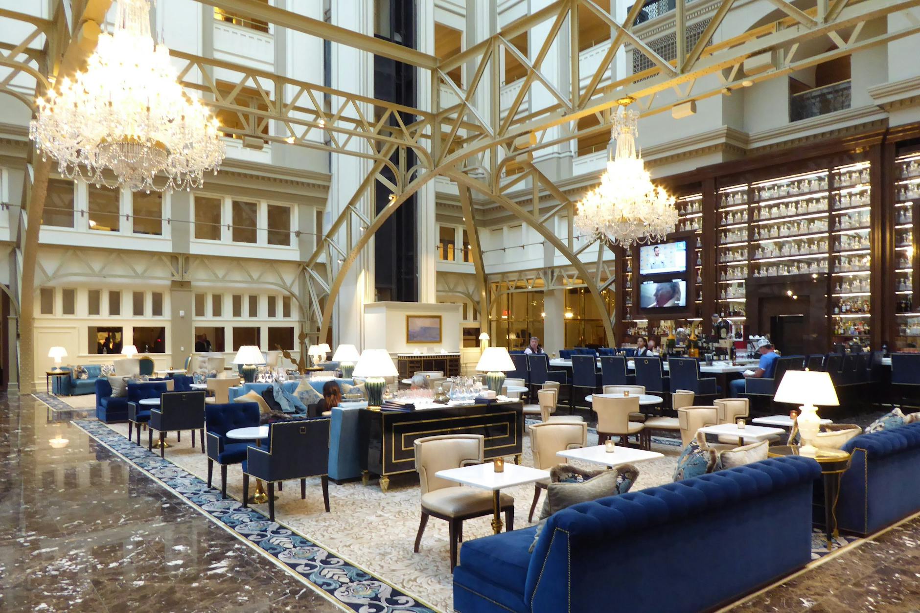 Blick in das glasüberdachte Atrium des Hotels: satte Polster, glitzernde Kronleuchter